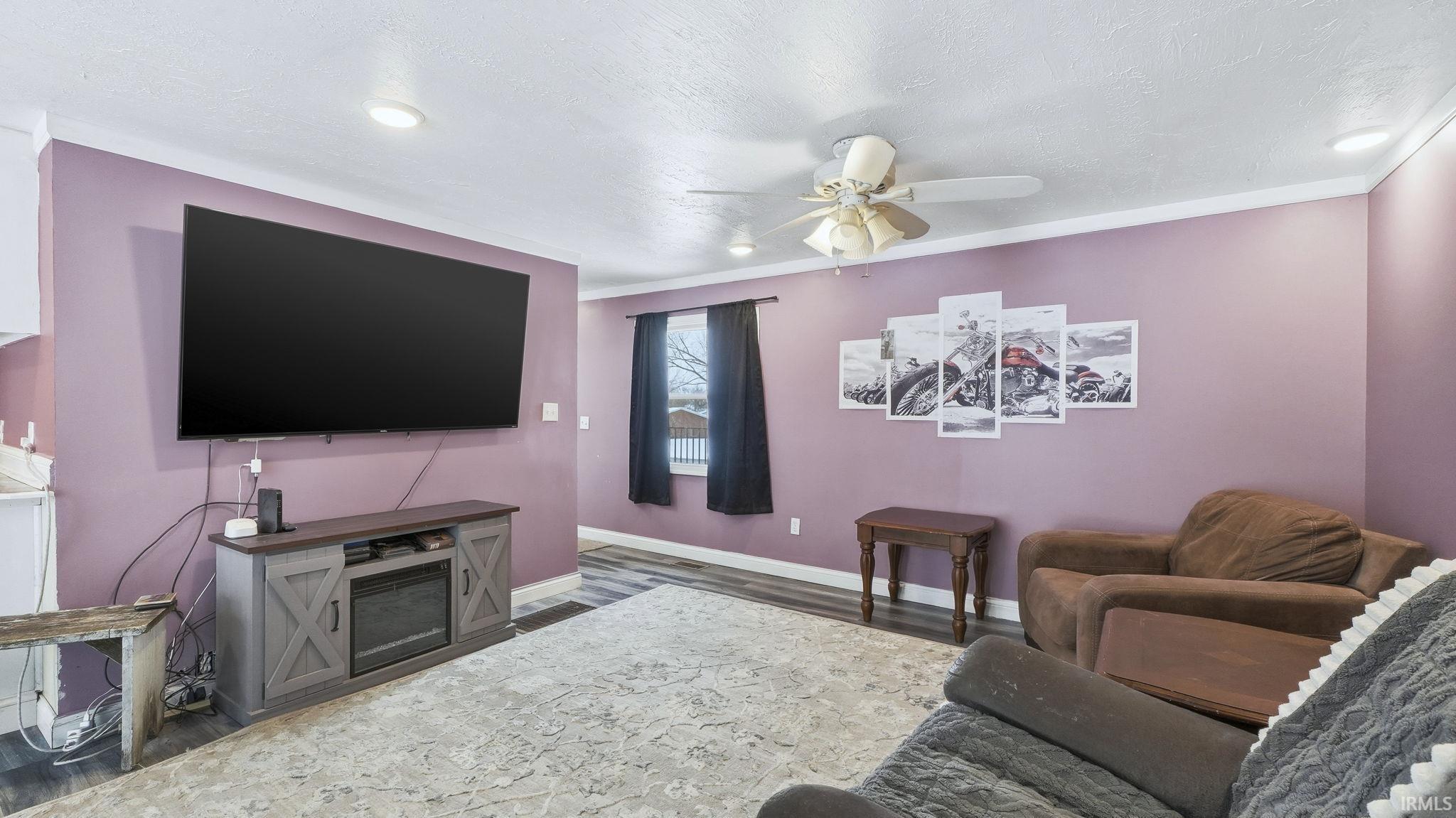Living room with ceiling fan, wood finished floors, and a textured ceiling