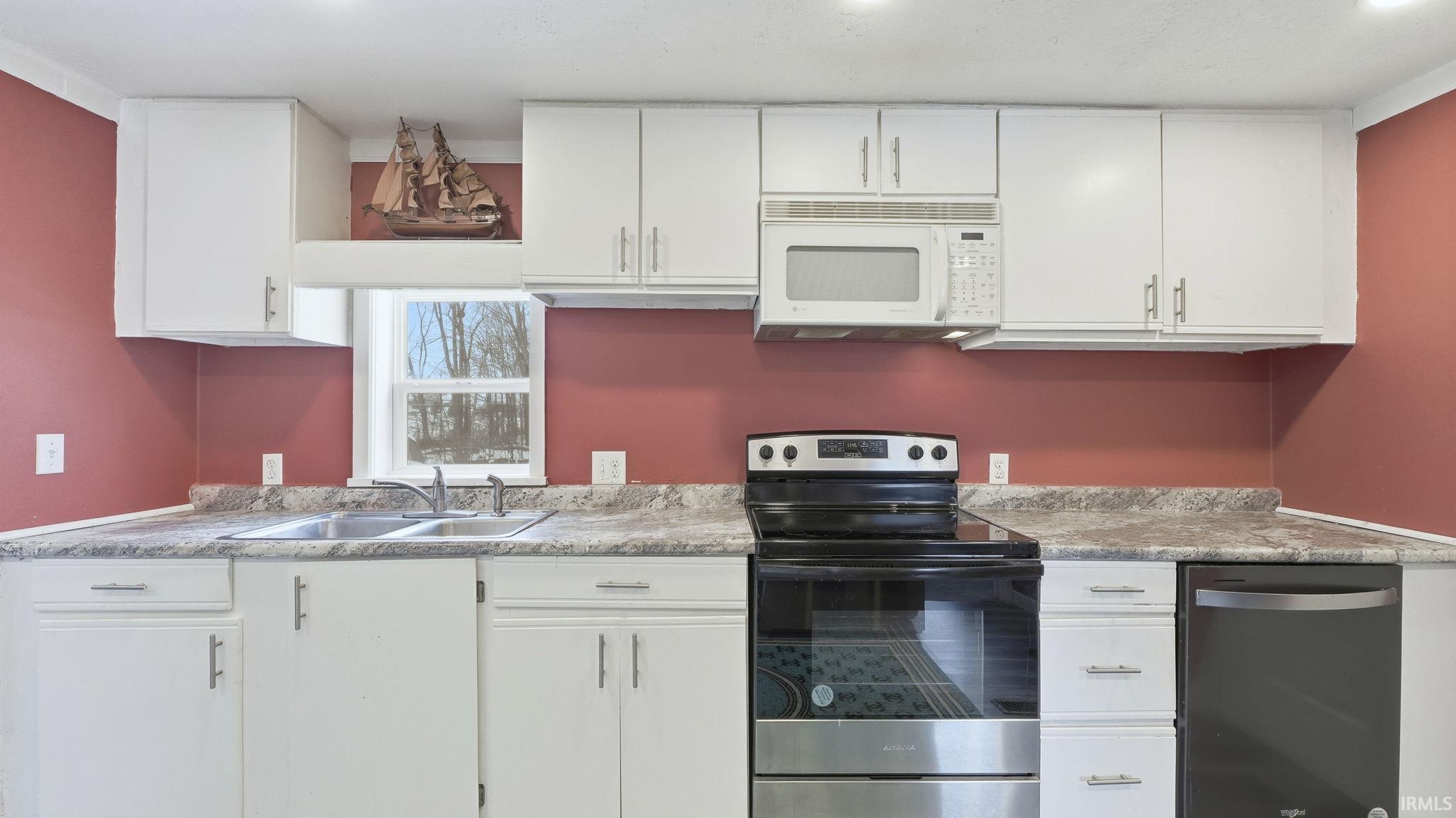 Kitchen featuring stainless steel appliances, white cabinets, and light countertops