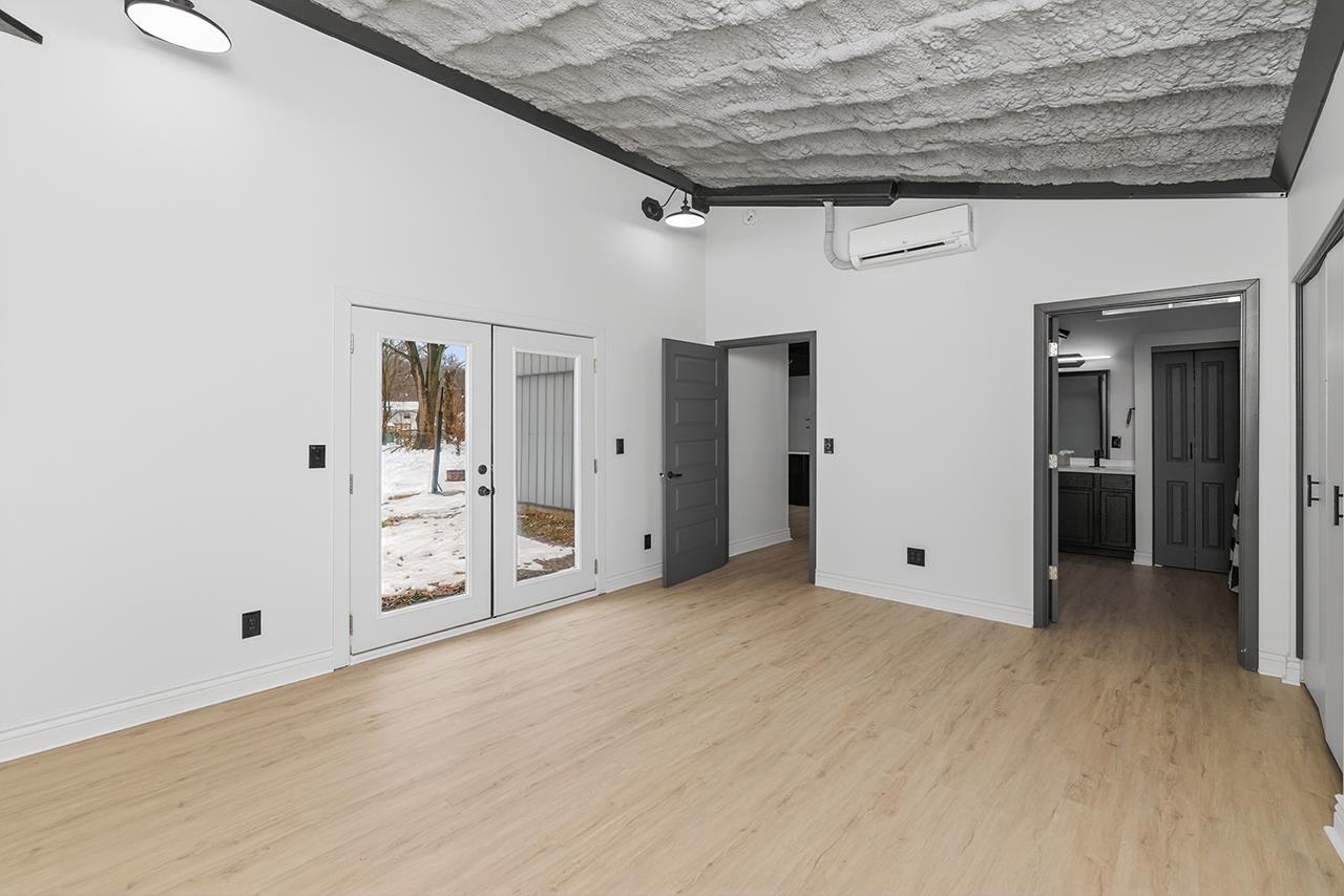 Spare room with french doors, light wood-style floors, and a wall mounted AC