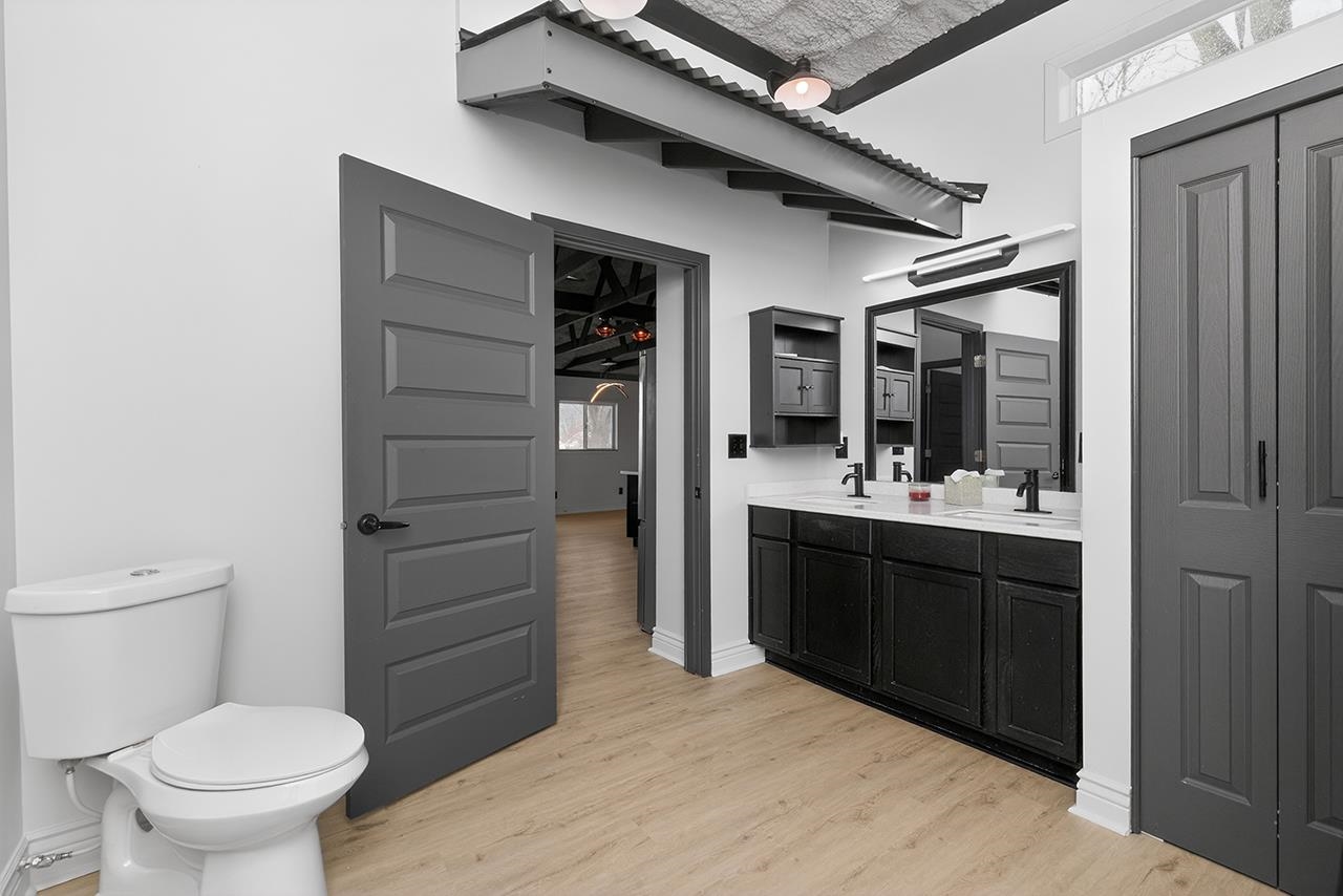 Bathroom with double vanity, a closet, and light wood-type flooring