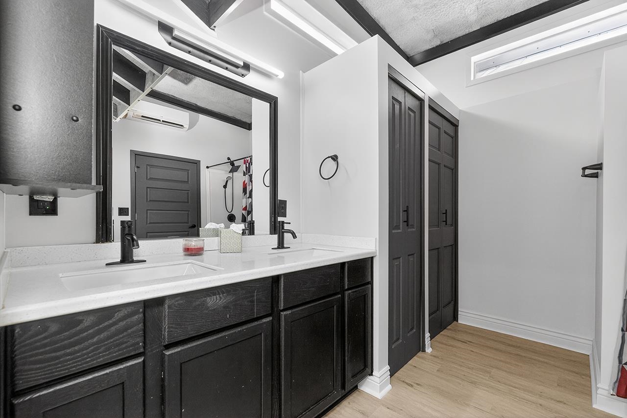 Bathroom with double vanity, light wood finished floors, a wall mounted AC, and a closet