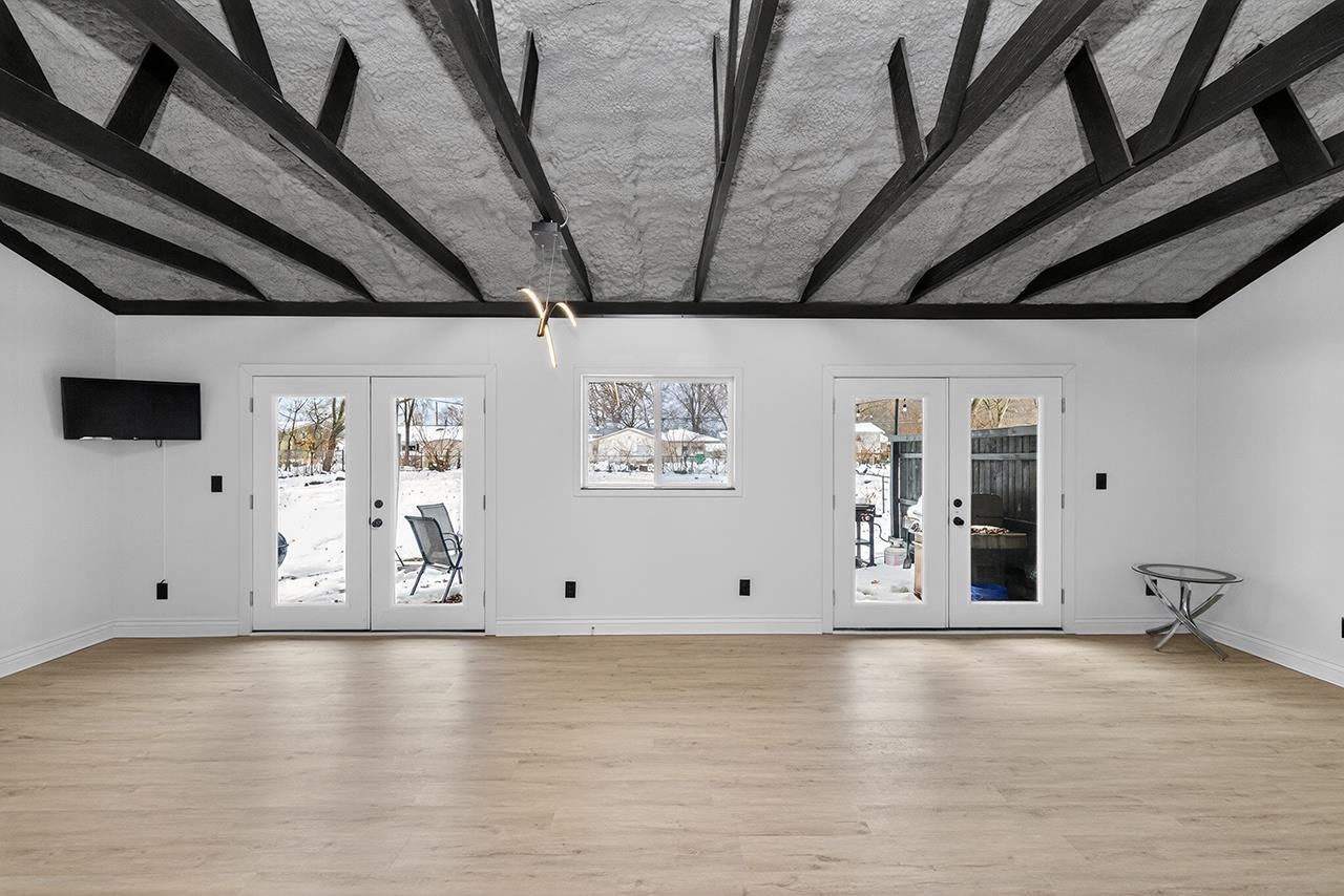 Unfurnished living room with french doors, vaulted ceiling, and light wood-style flooring