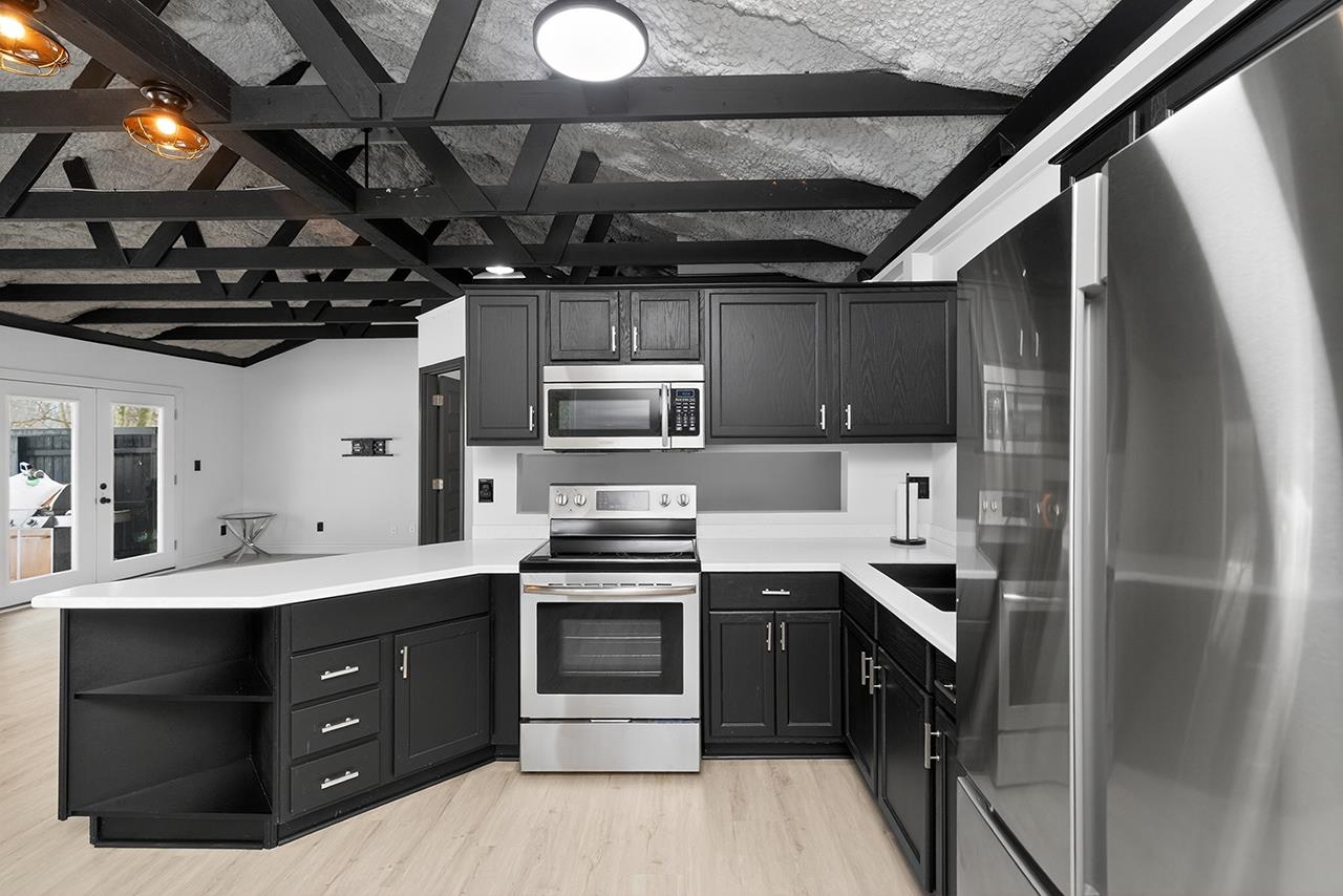 Kitchen featuring appliances with stainless steel finishes, a peninsula, french doors, open shelves, and light wood finished floors