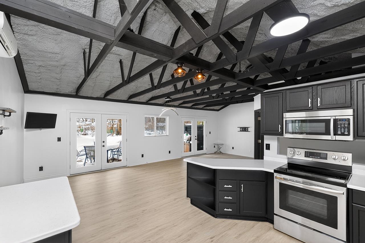 Kitchen featuring french doors, appliances with stainless steel finishes, a peninsula, open floor plan, and vaulted ceiling