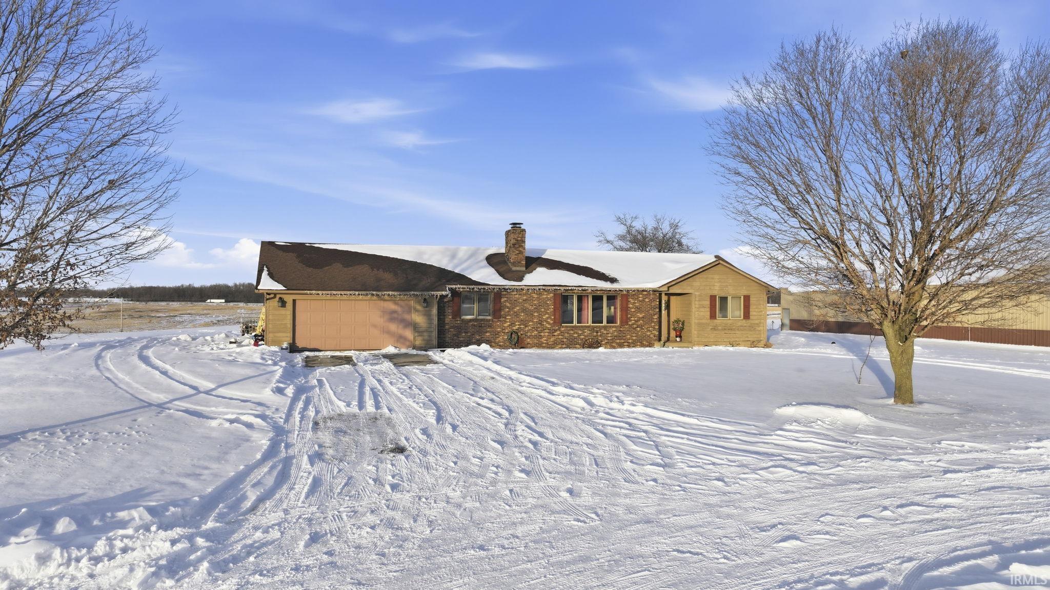 View of front of house featuring a chimney, an attached garage, and brick siding