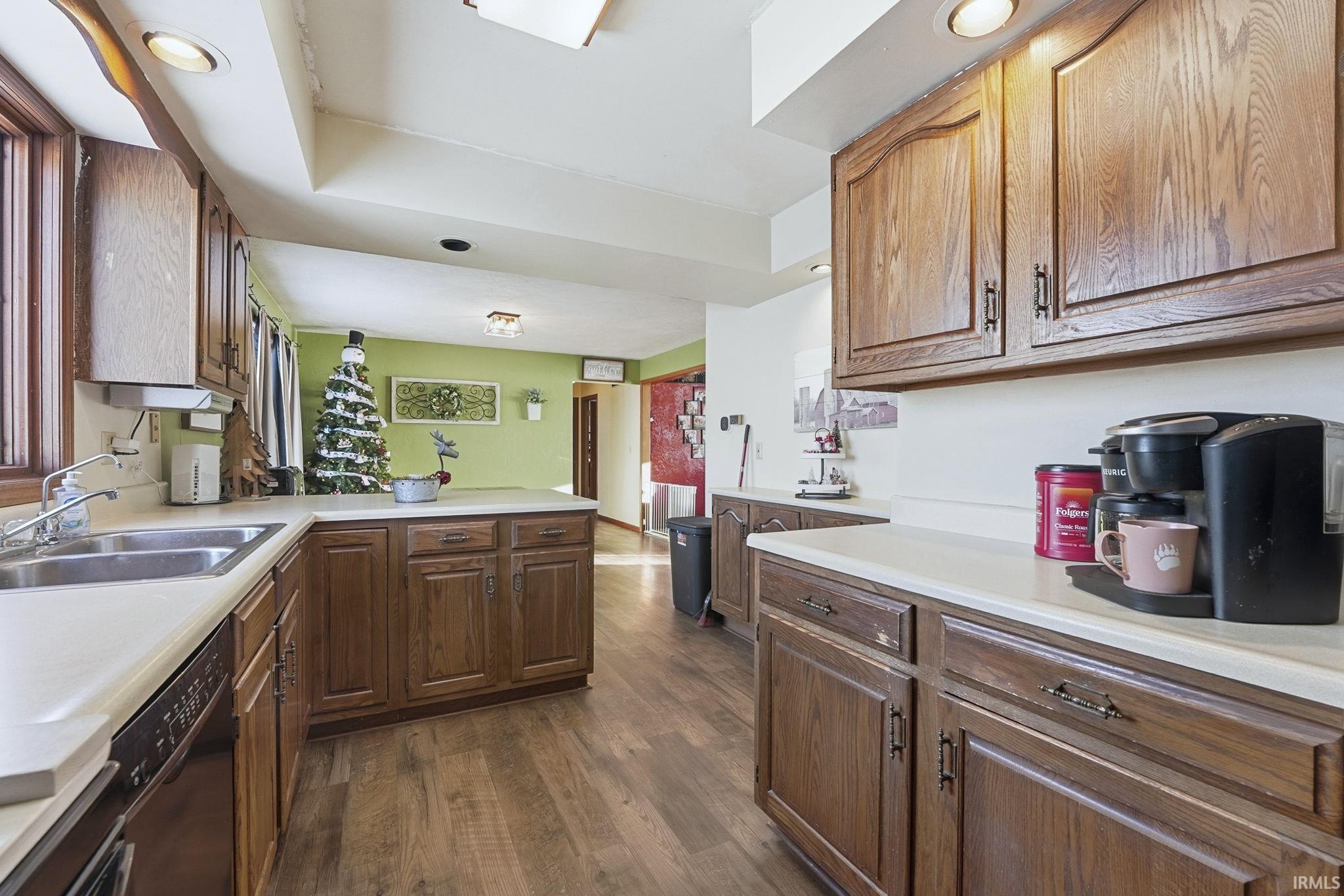 Kitchen with light countertops, dark wood finished floors, black dishwasher, a peninsula, and recessed lighting