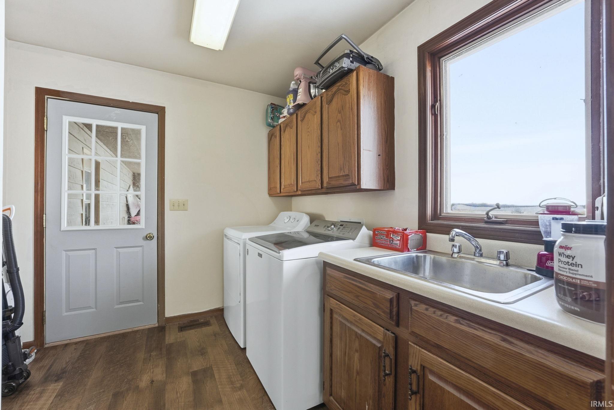 Washroom featuring cabinet space, dark wood finished floors, and washer and dryer