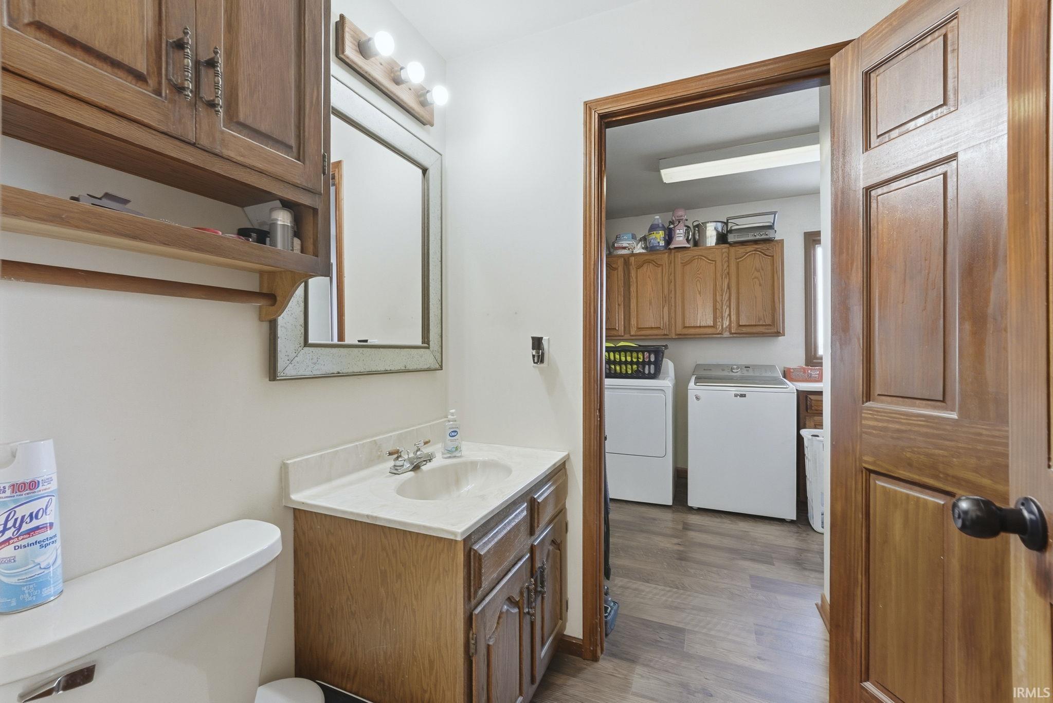 Half bath featuring vanity, independent washer and dryer, and dark wood-style floors