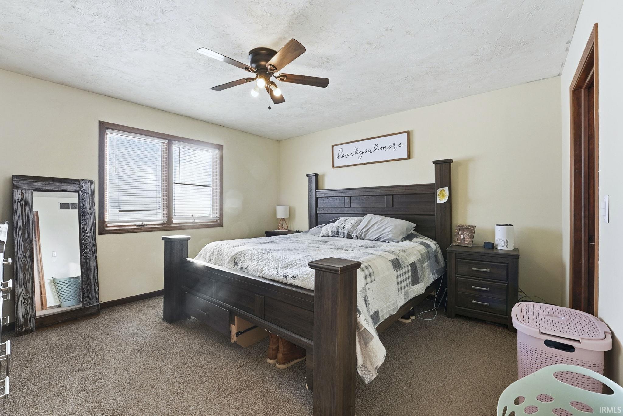 Bedroom with carpet flooring, ceiling fan, and a textured ceiling
