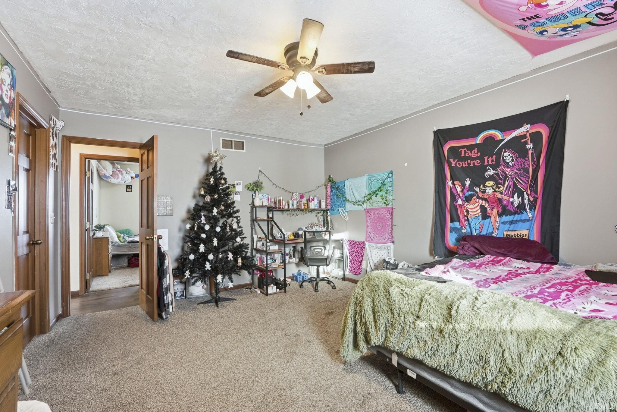 Carpeted bedroom with a textured ceiling and ceiling fan