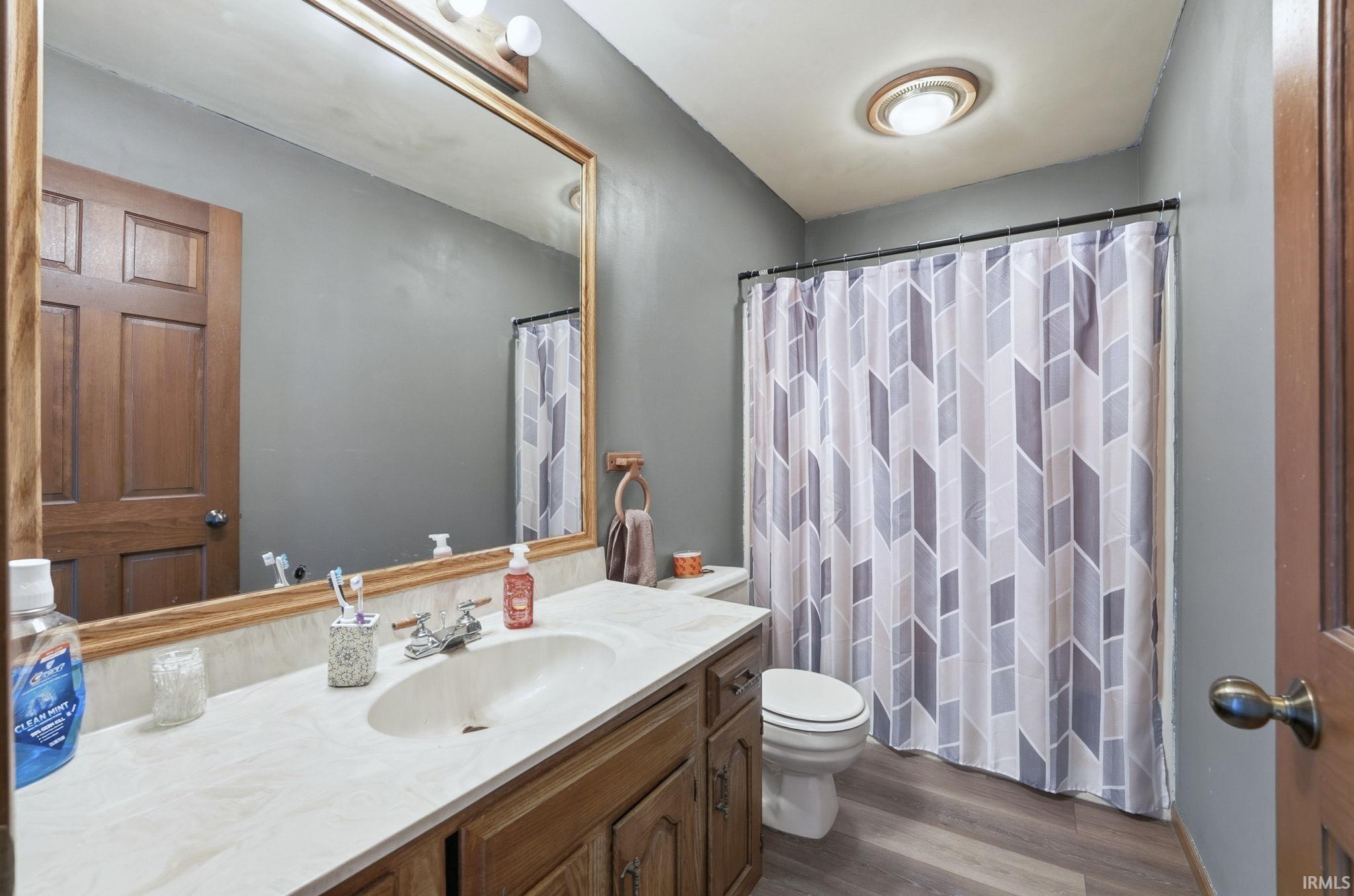 Bathroom with a shower with shower curtain, dark wood-type flooring, and vanity