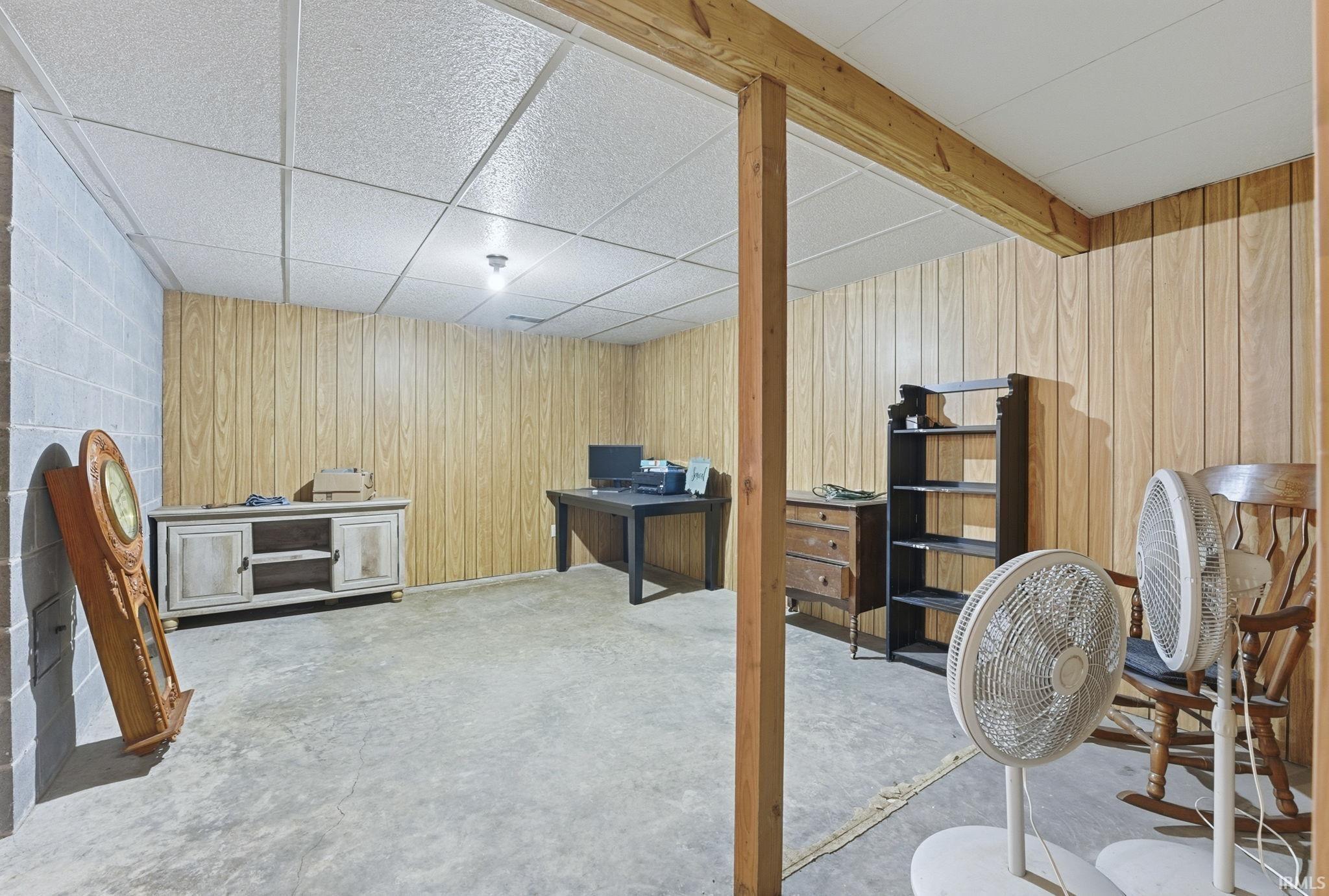 Finished basement featuring a paneled ceiling and wood walls