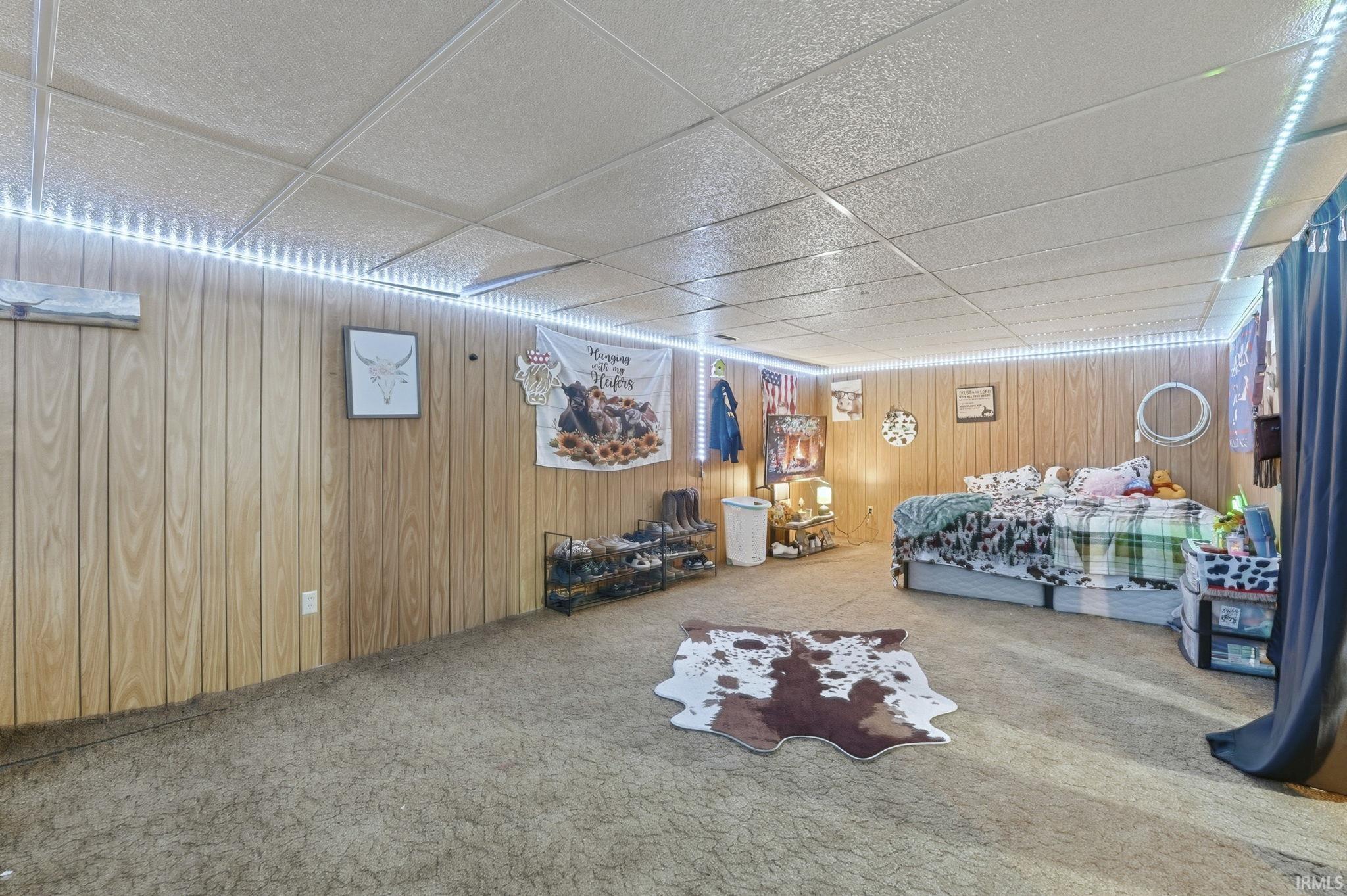 Bedroom with a paneled ceiling, carpet floors, and wood walls