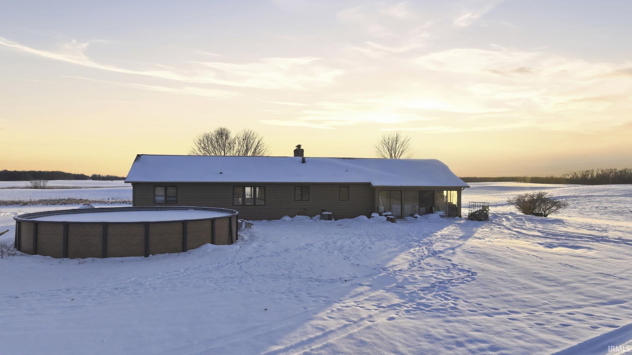 Snow covered property featuring a chimney and a sunroom