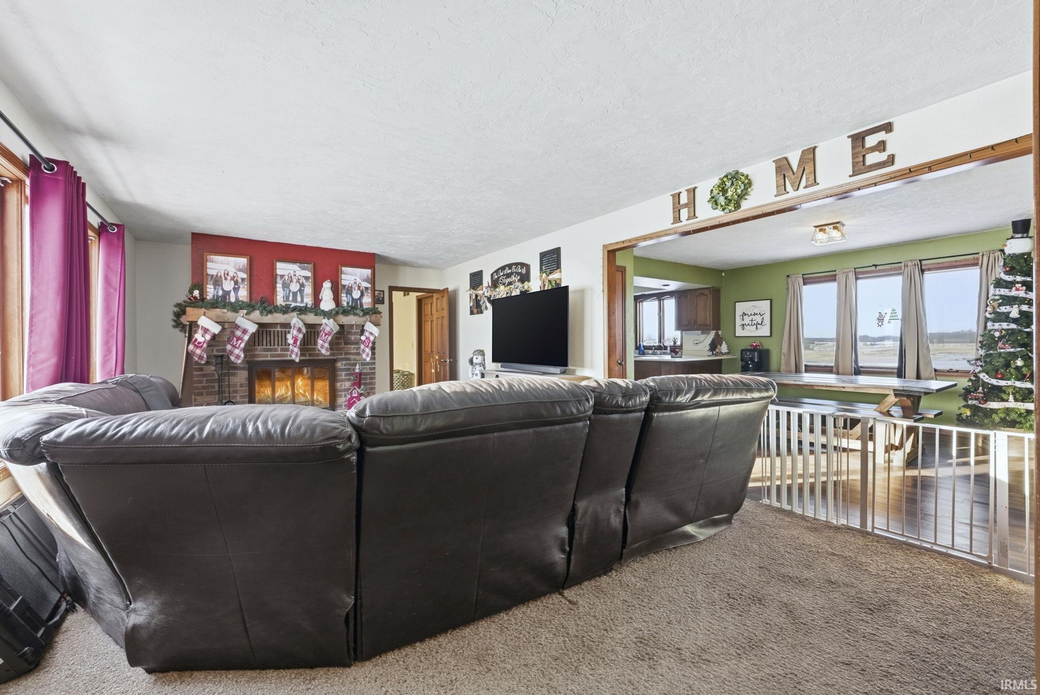 Carpeted living room featuring a brick fireplace and a textured ceiling