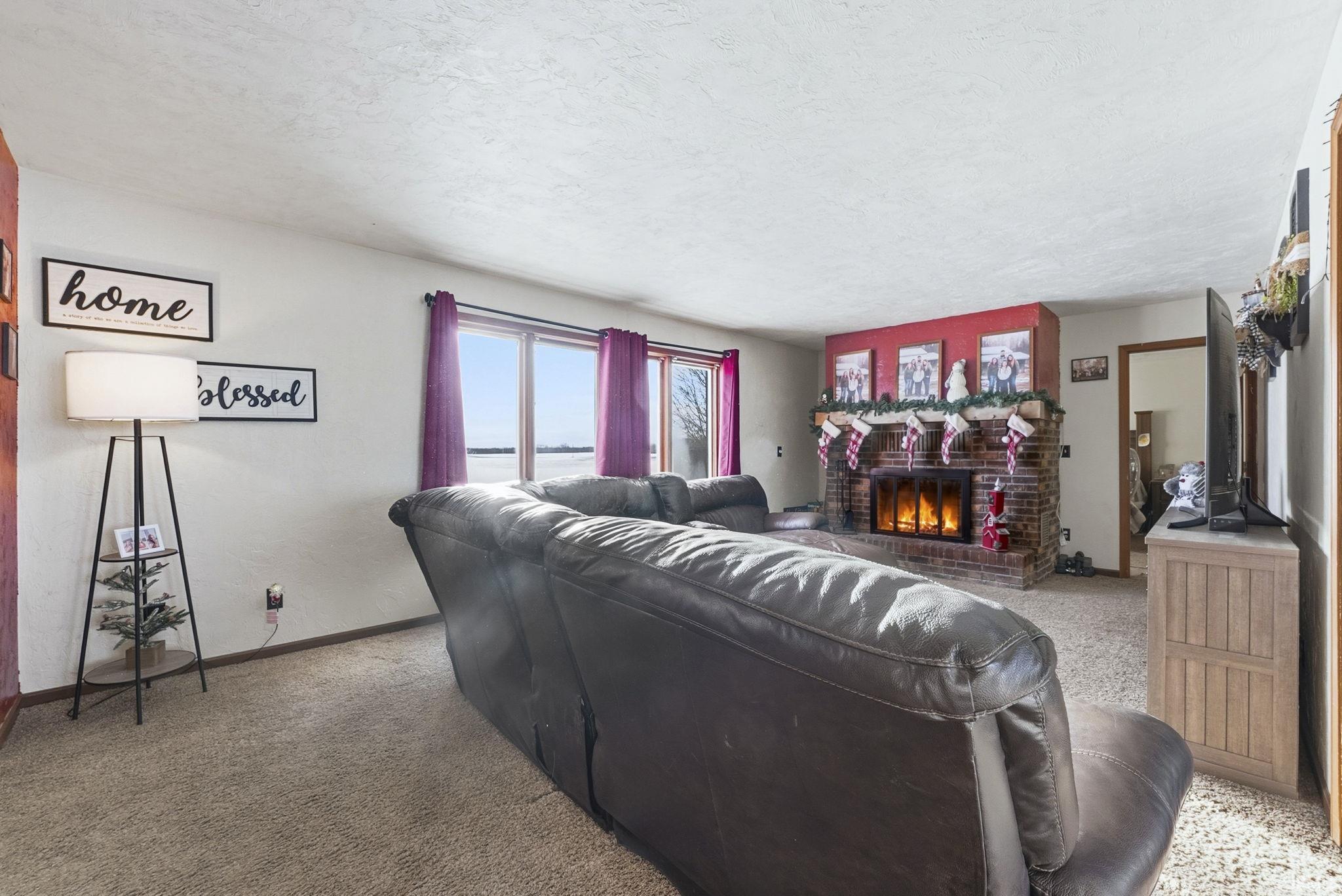 Living room featuring a brick fireplace, carpet, and a textured ceiling