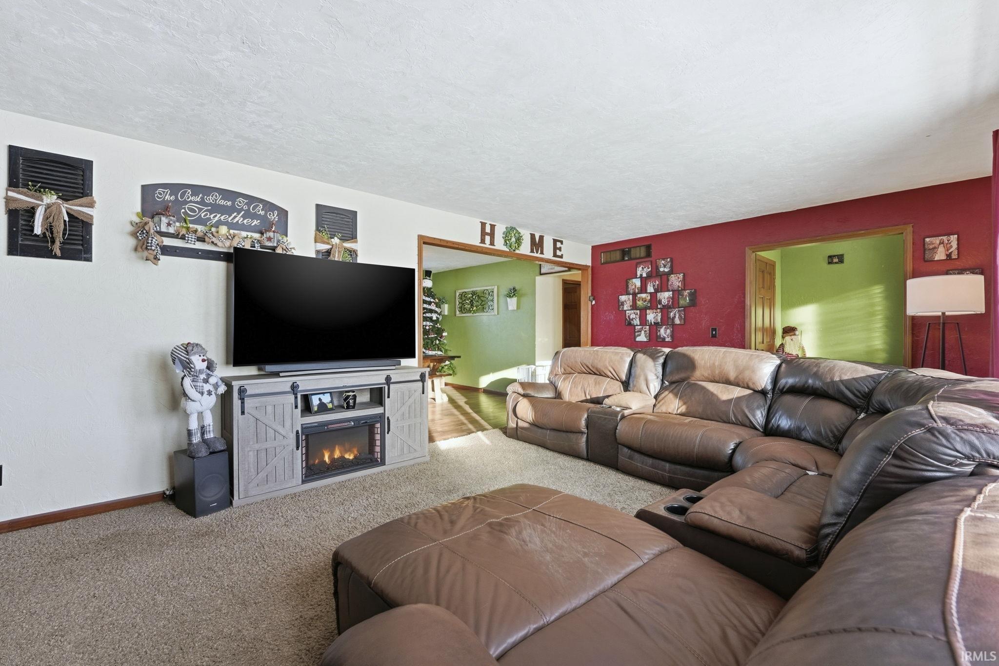 Carpeted living area featuring a lit fireplace and a textured ceiling