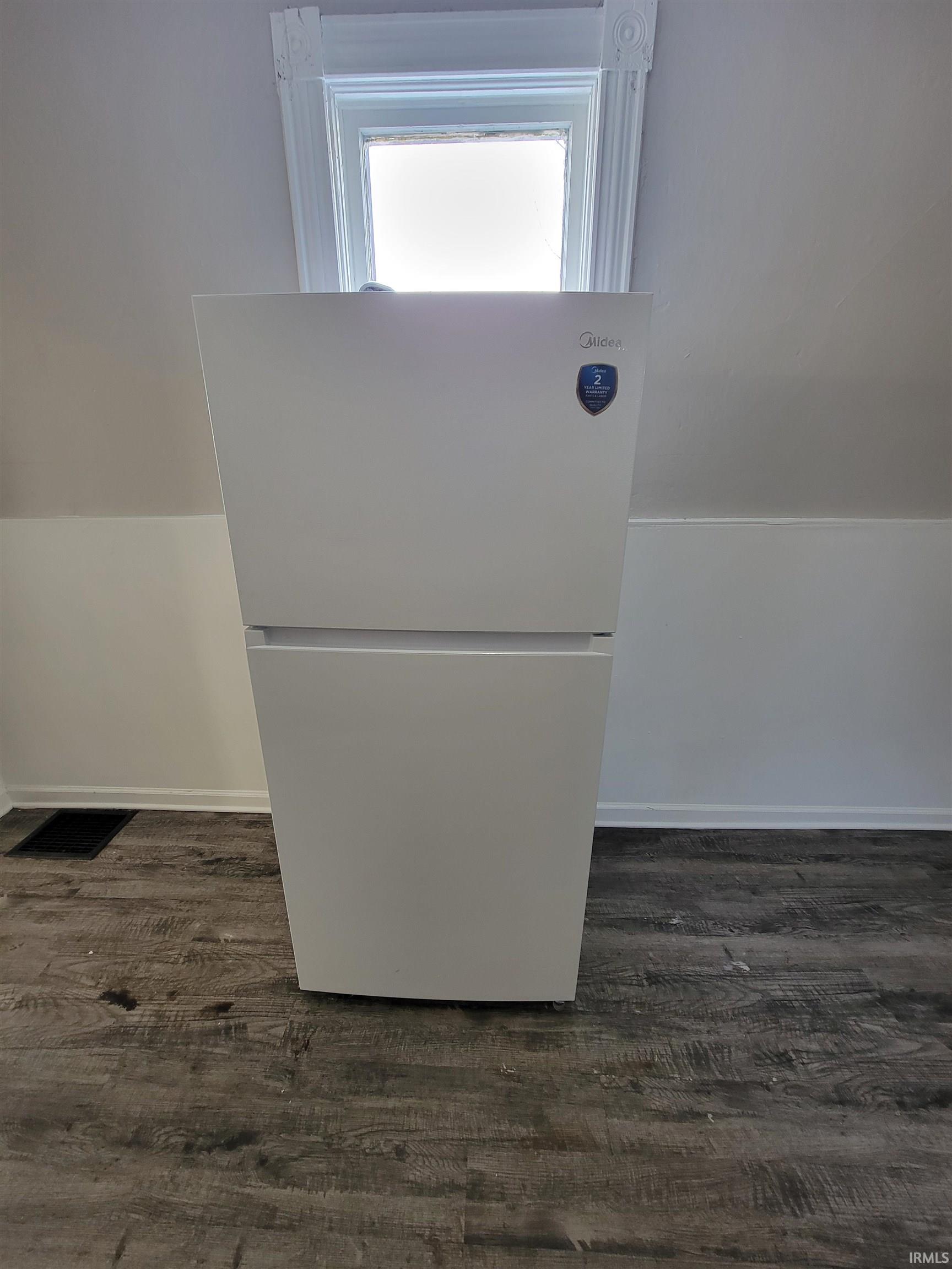 Detailed view of freestanding refrigerator and wood finished floors
