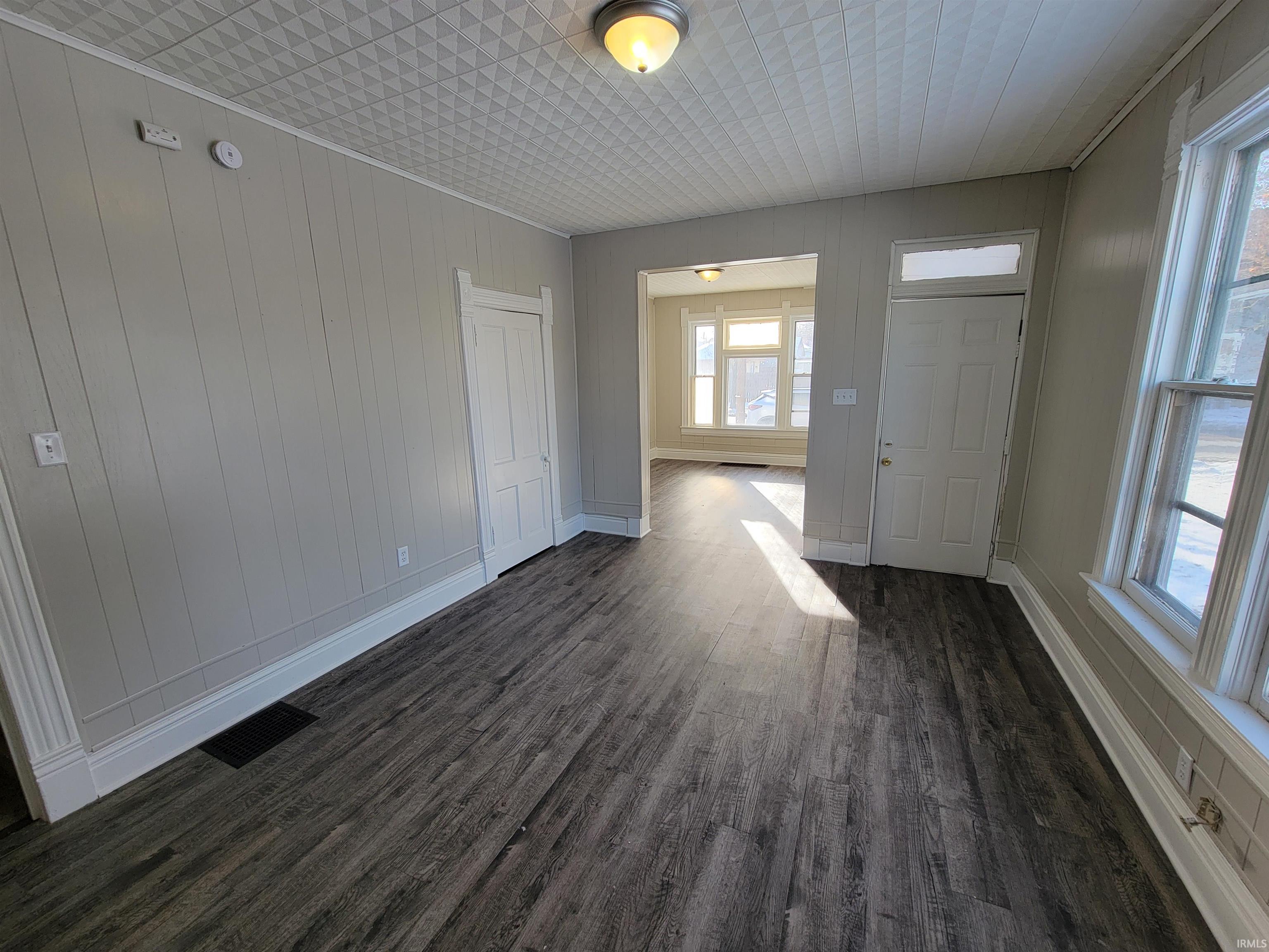Unfurnished living room featuring dark wood finished floors and wooden walls