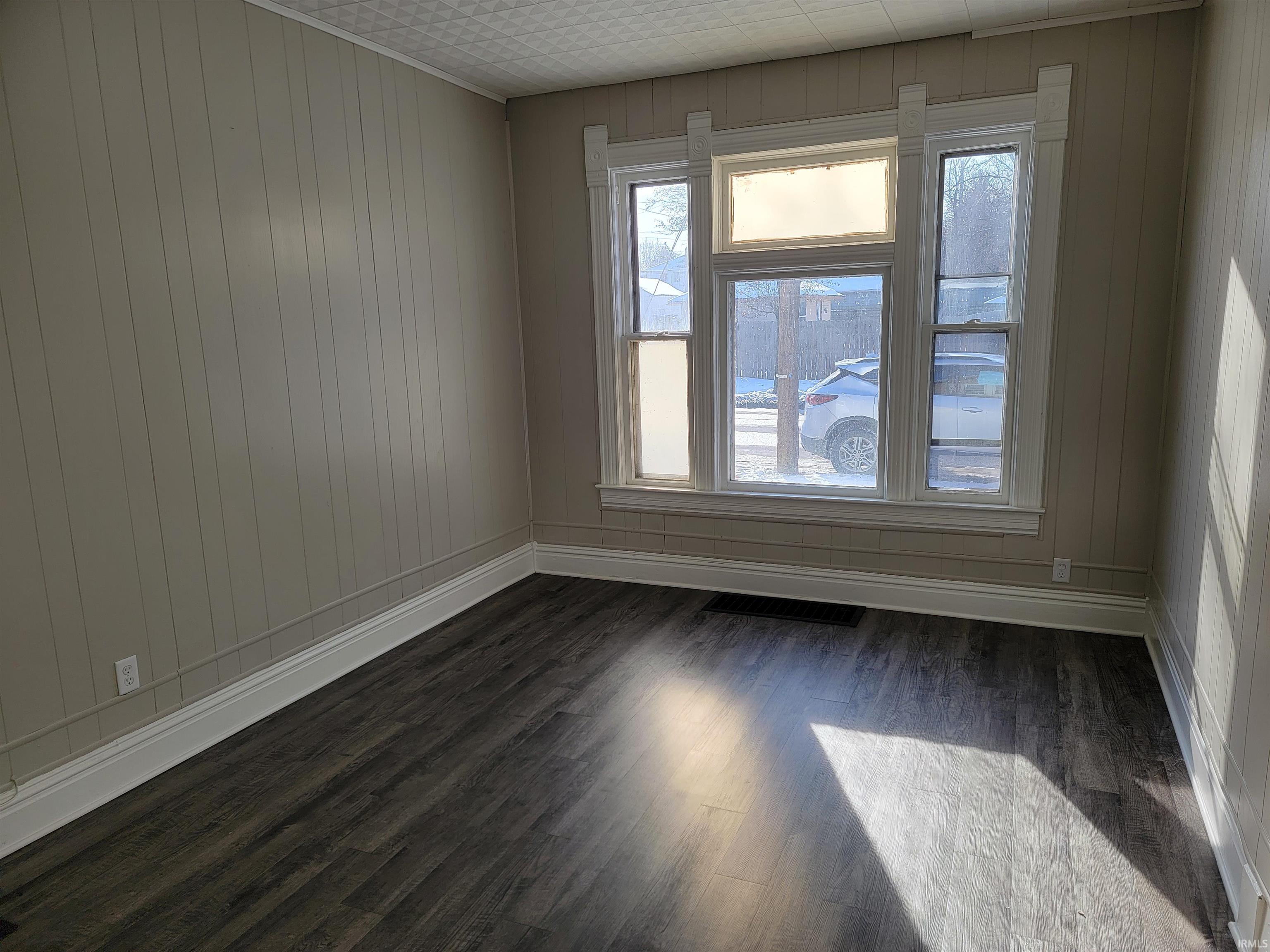 Spare room with dark wood finished floors and wood walls