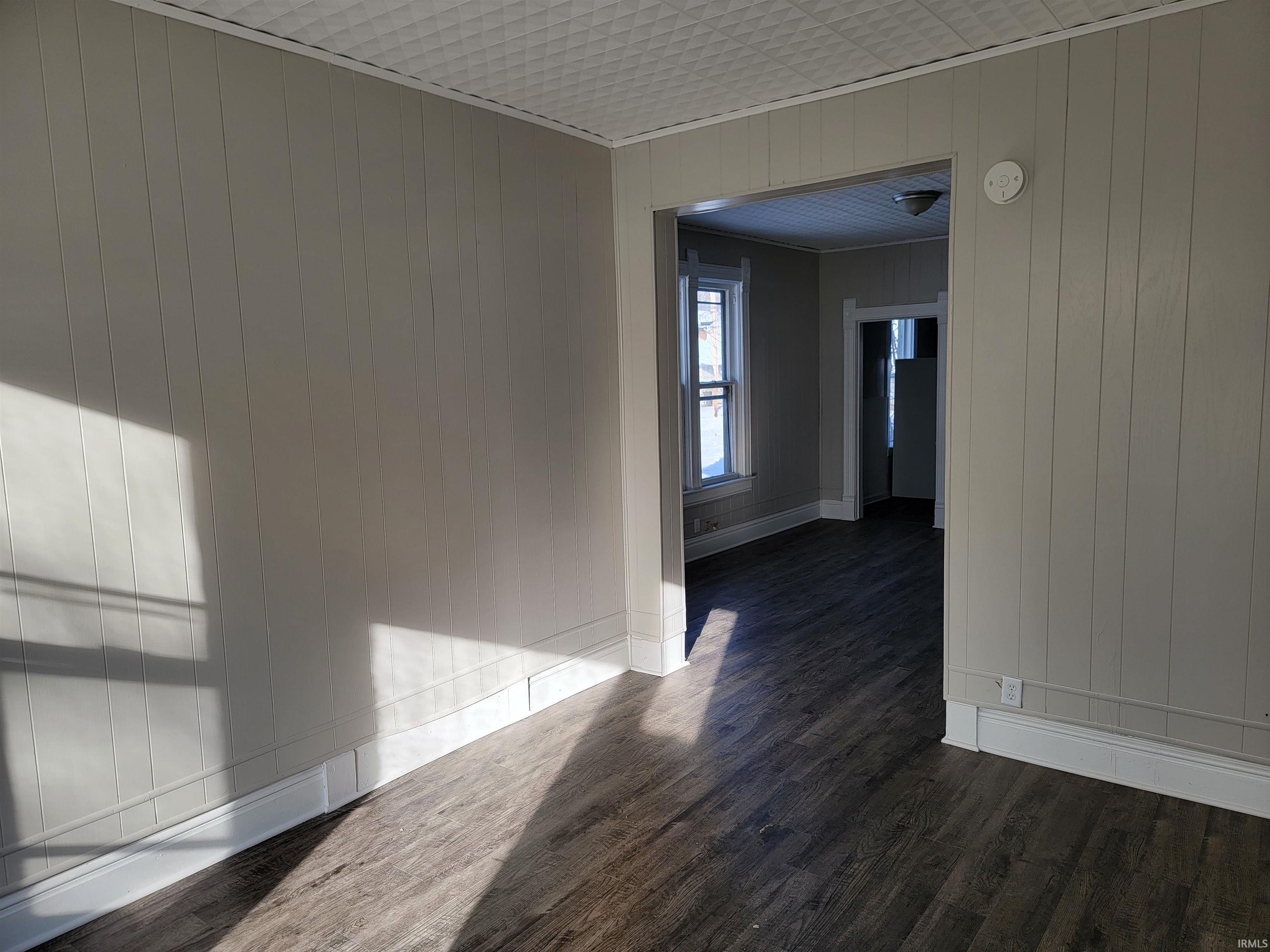 Empty room featuring wooden walls and dark wood-style flooring