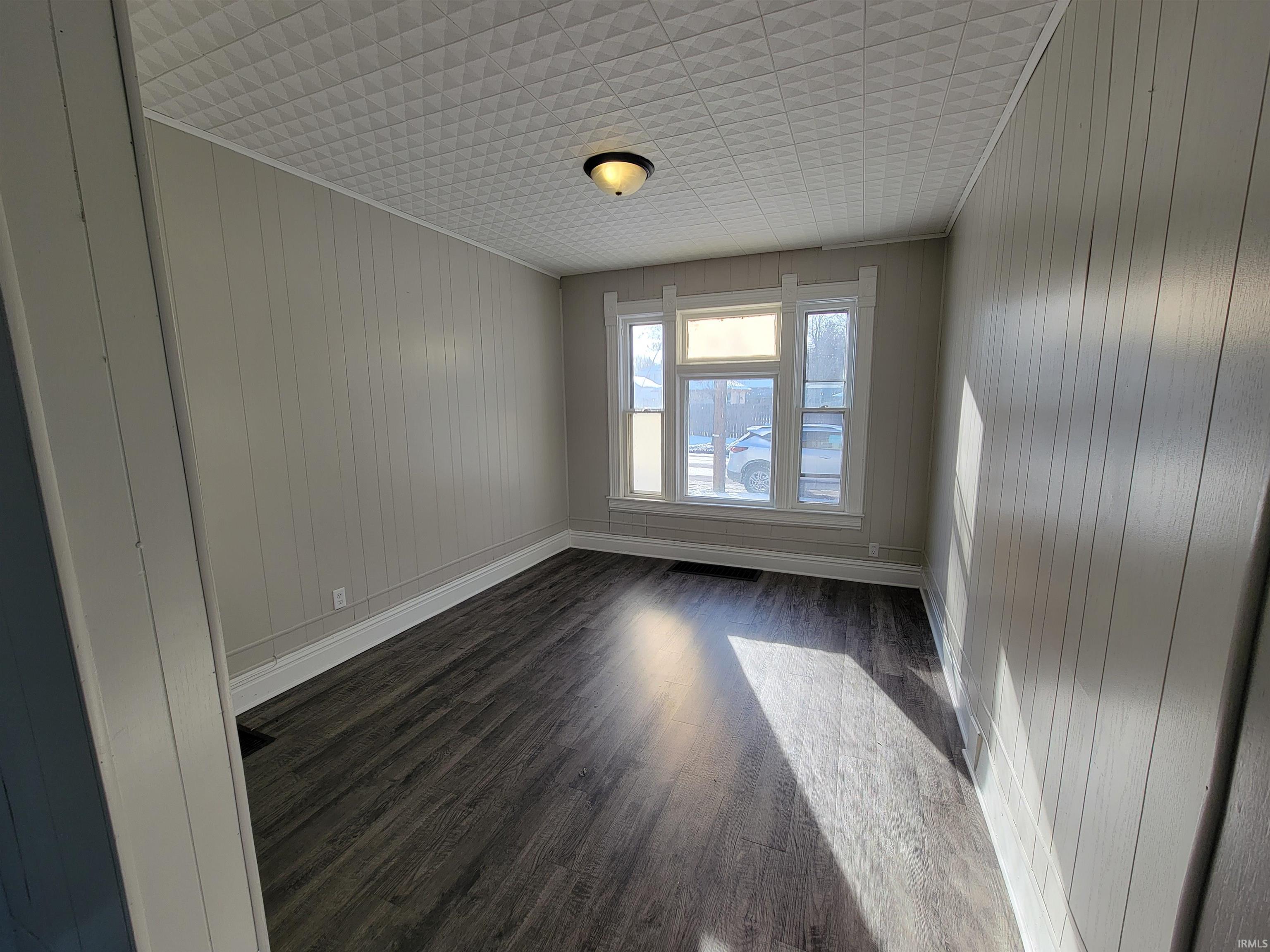 Empty room featuring dark wood finished floors and wood walls