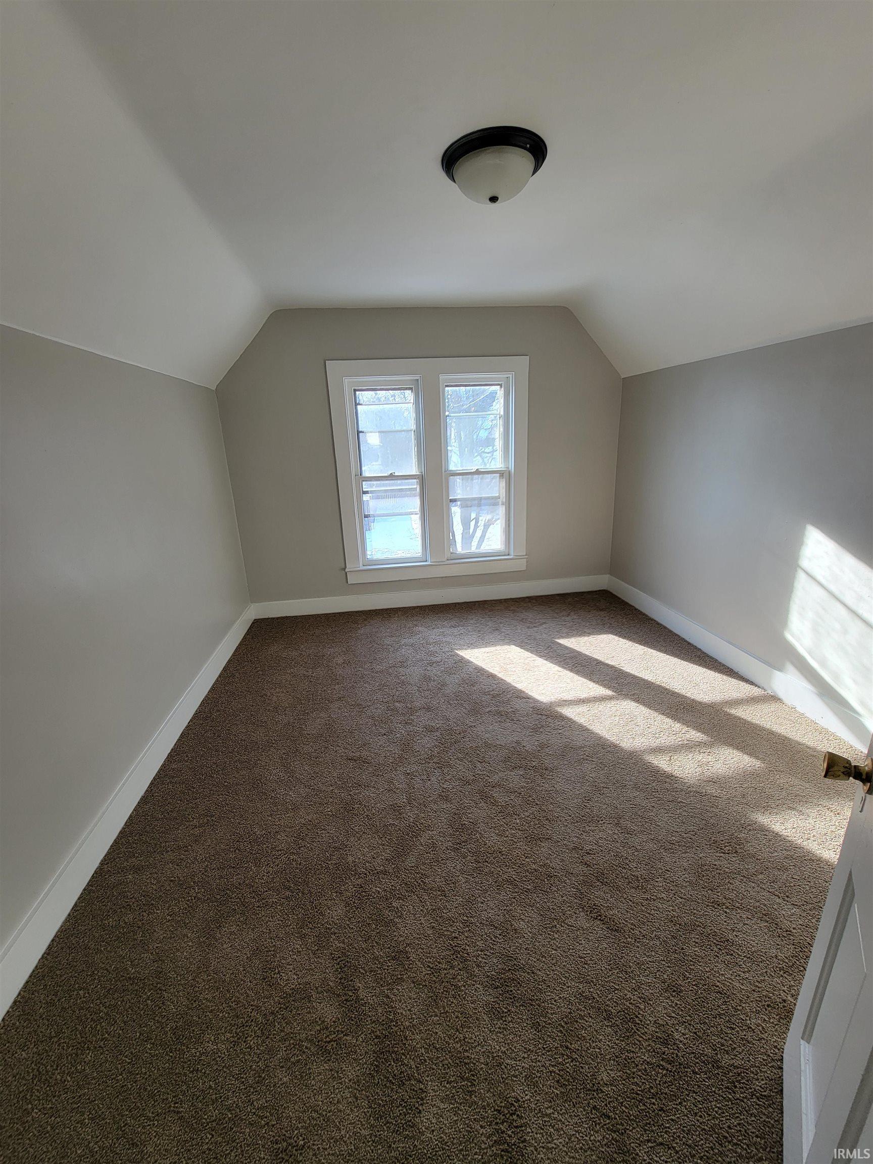 Additional living space with vaulted ceiling and carpet floors