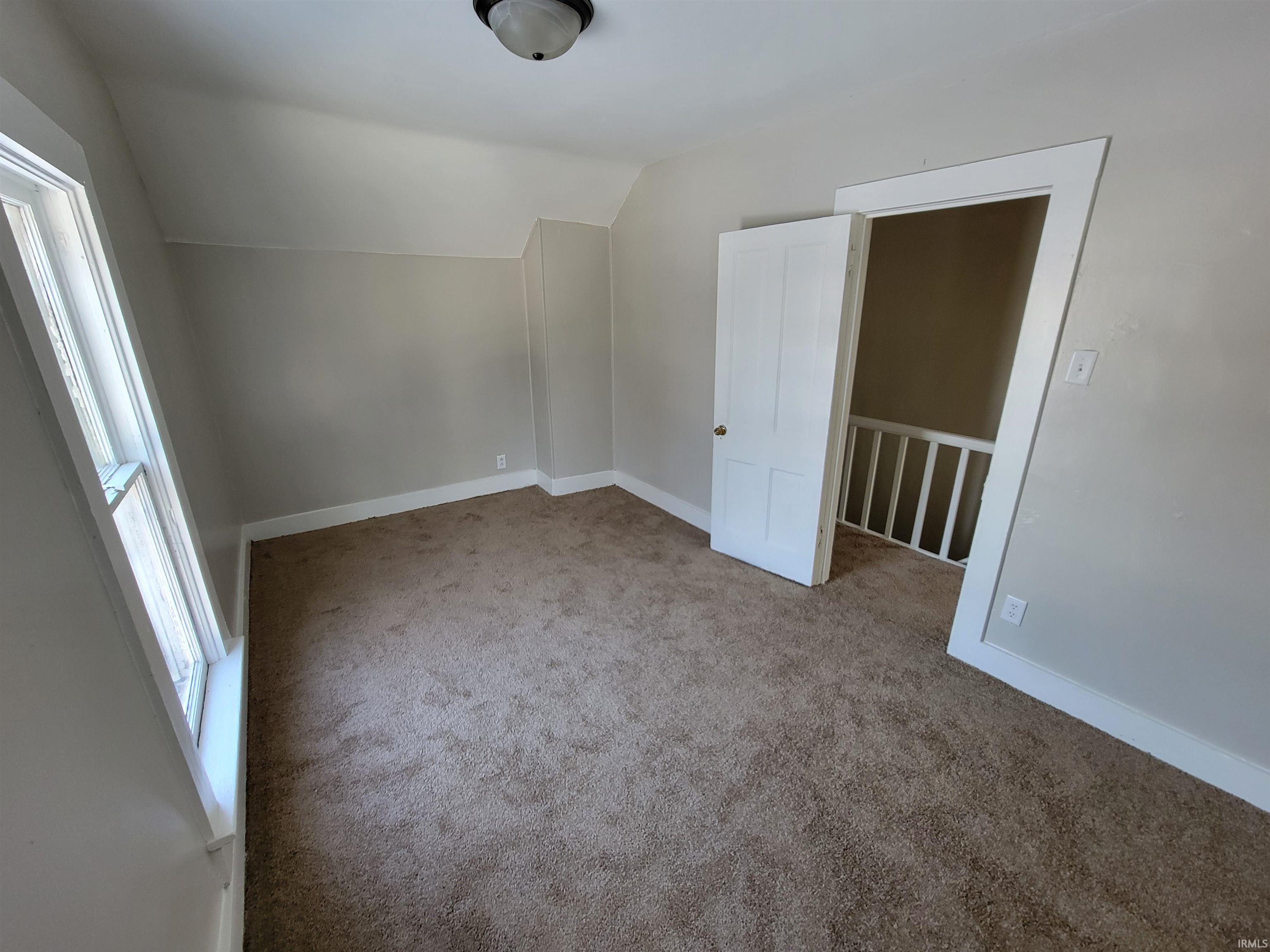 Additional living space featuring lofted ceiling and light colored carpet