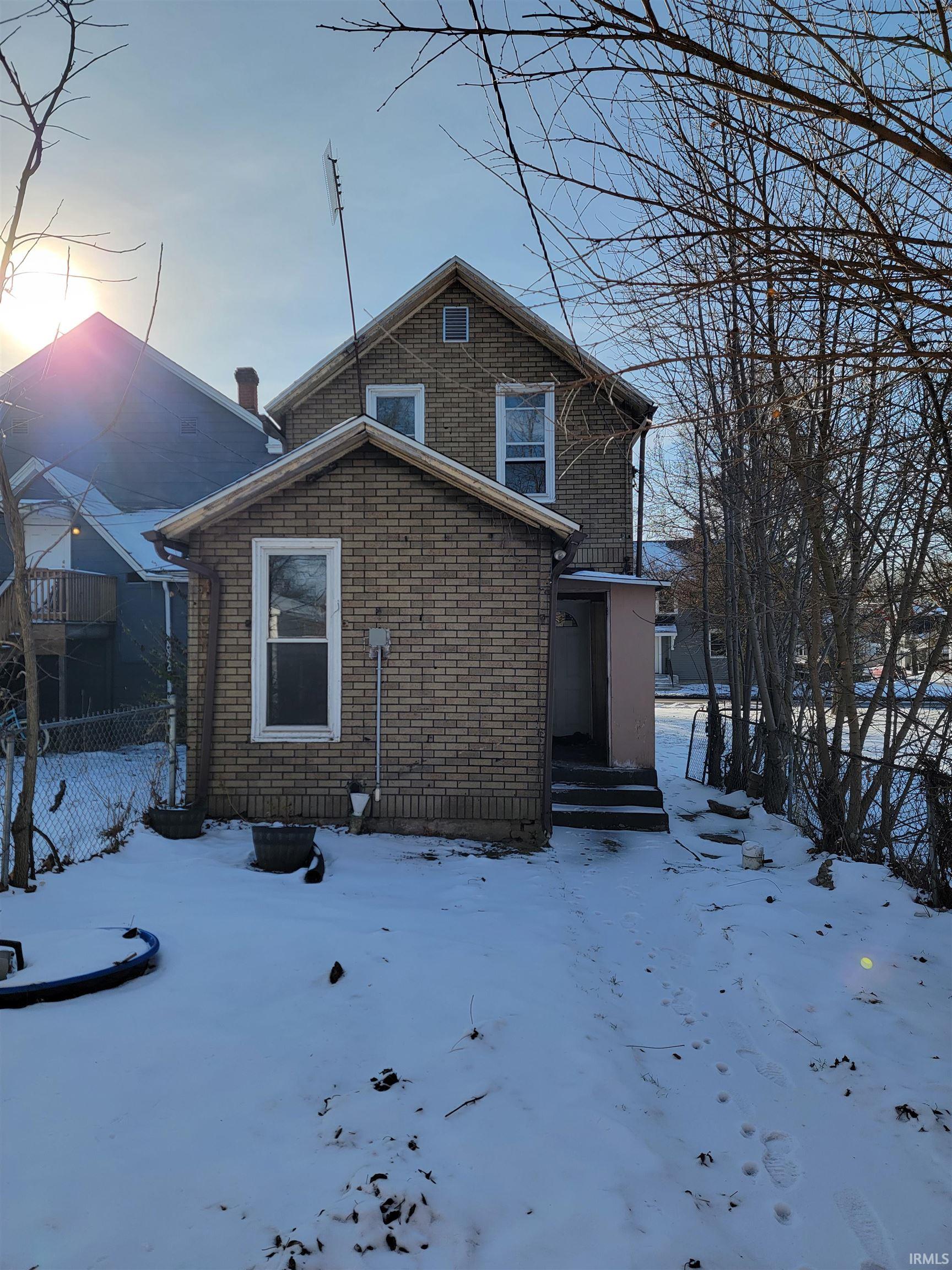 Snow covered rear of property with brick siding