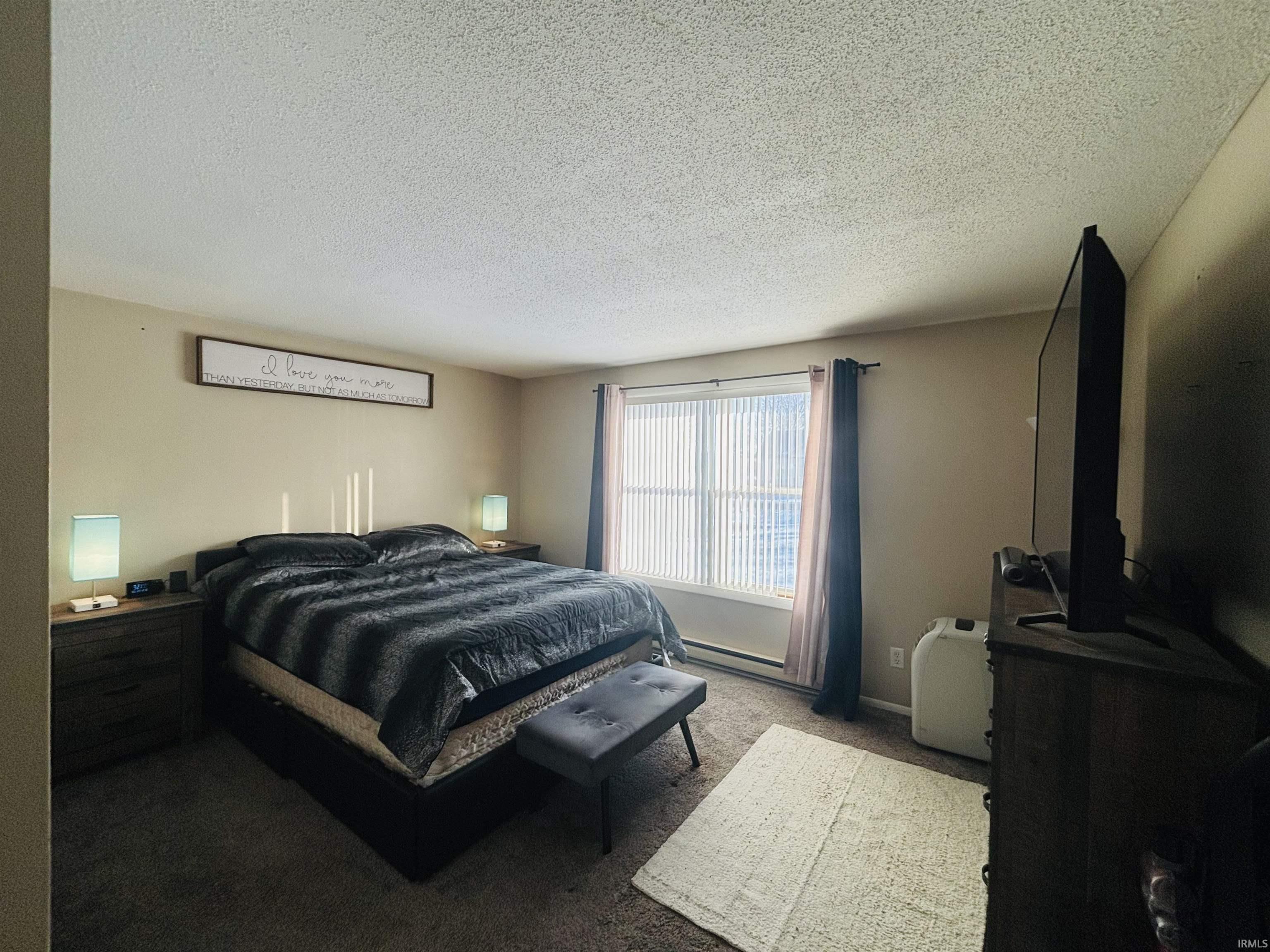 Bedroom with a textured ceiling and carpet flooring