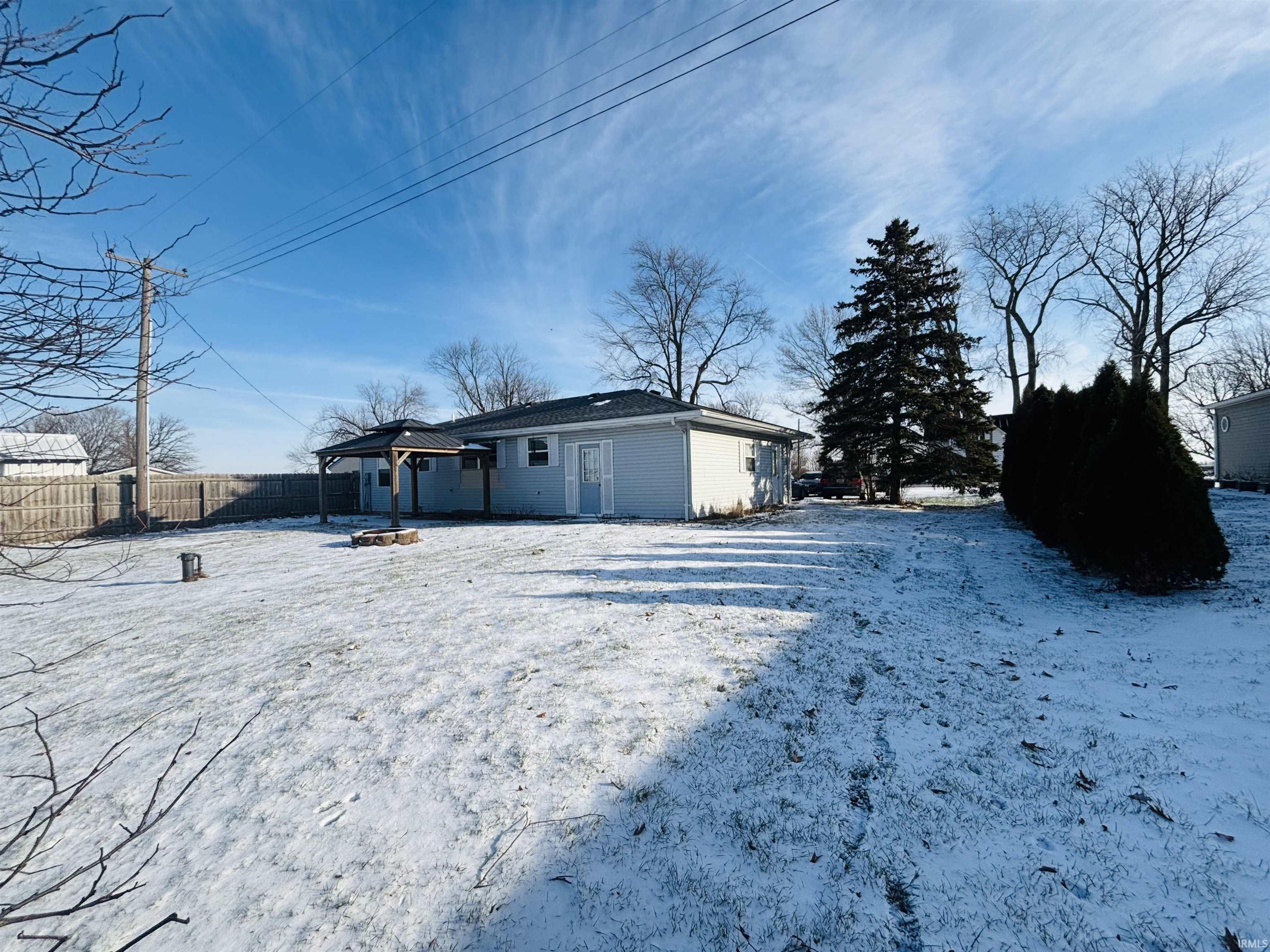 Snow covered back of property with a fire pit, a fenced backyard, a patio area, and a gazebo