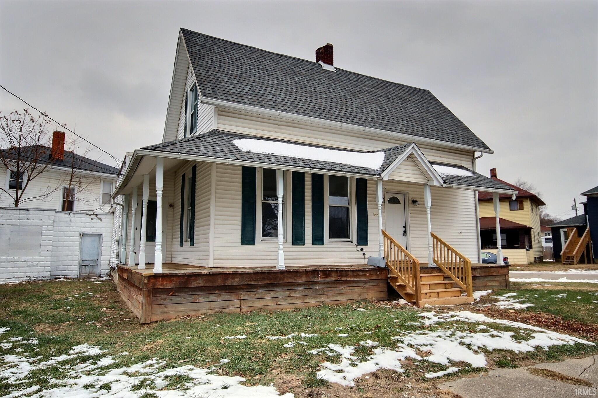 View of front of property featuring covered porch, a shingled roof, and a chimney