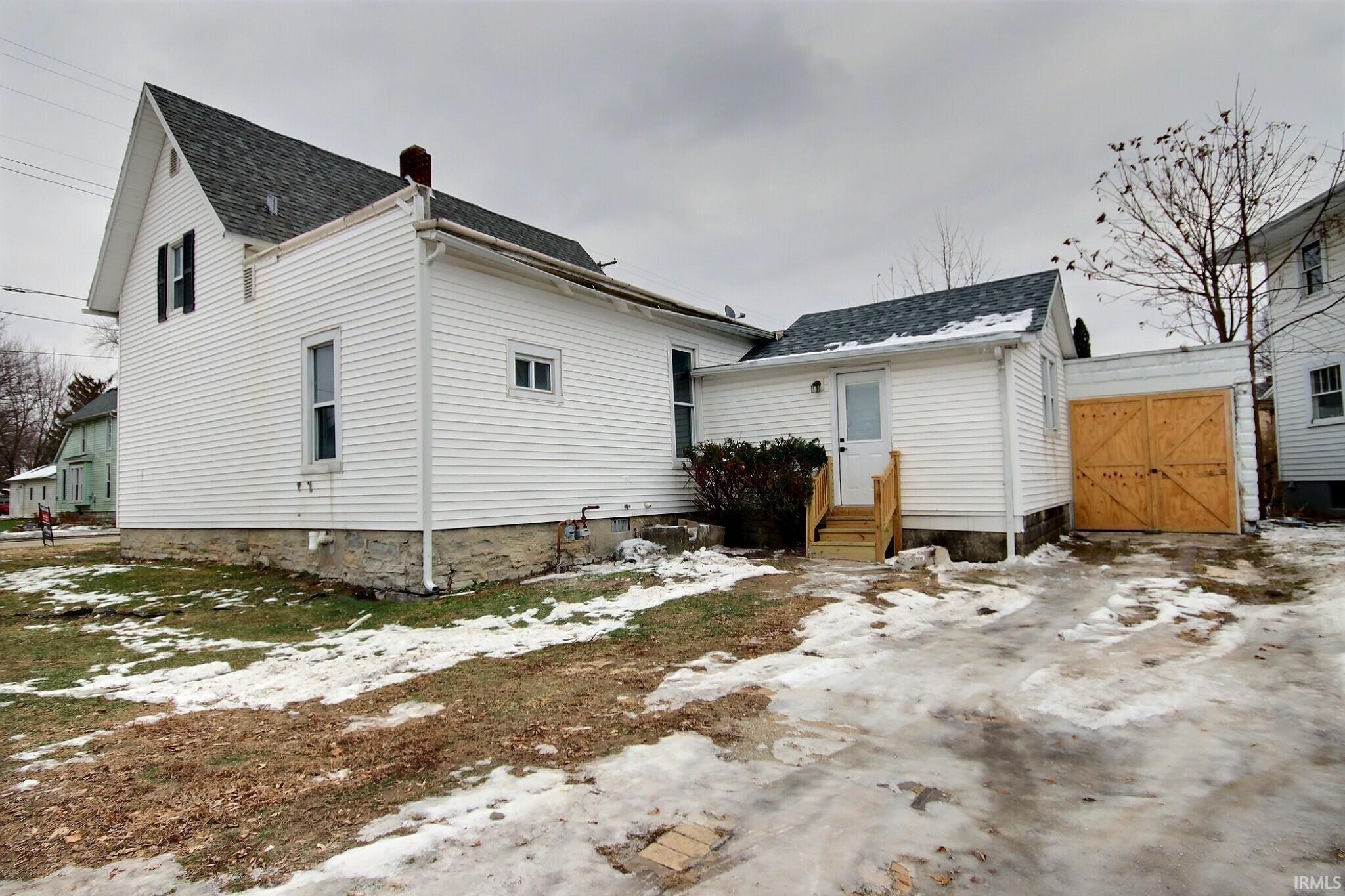 Snow covered property featuring a chimney and roof with shingles
