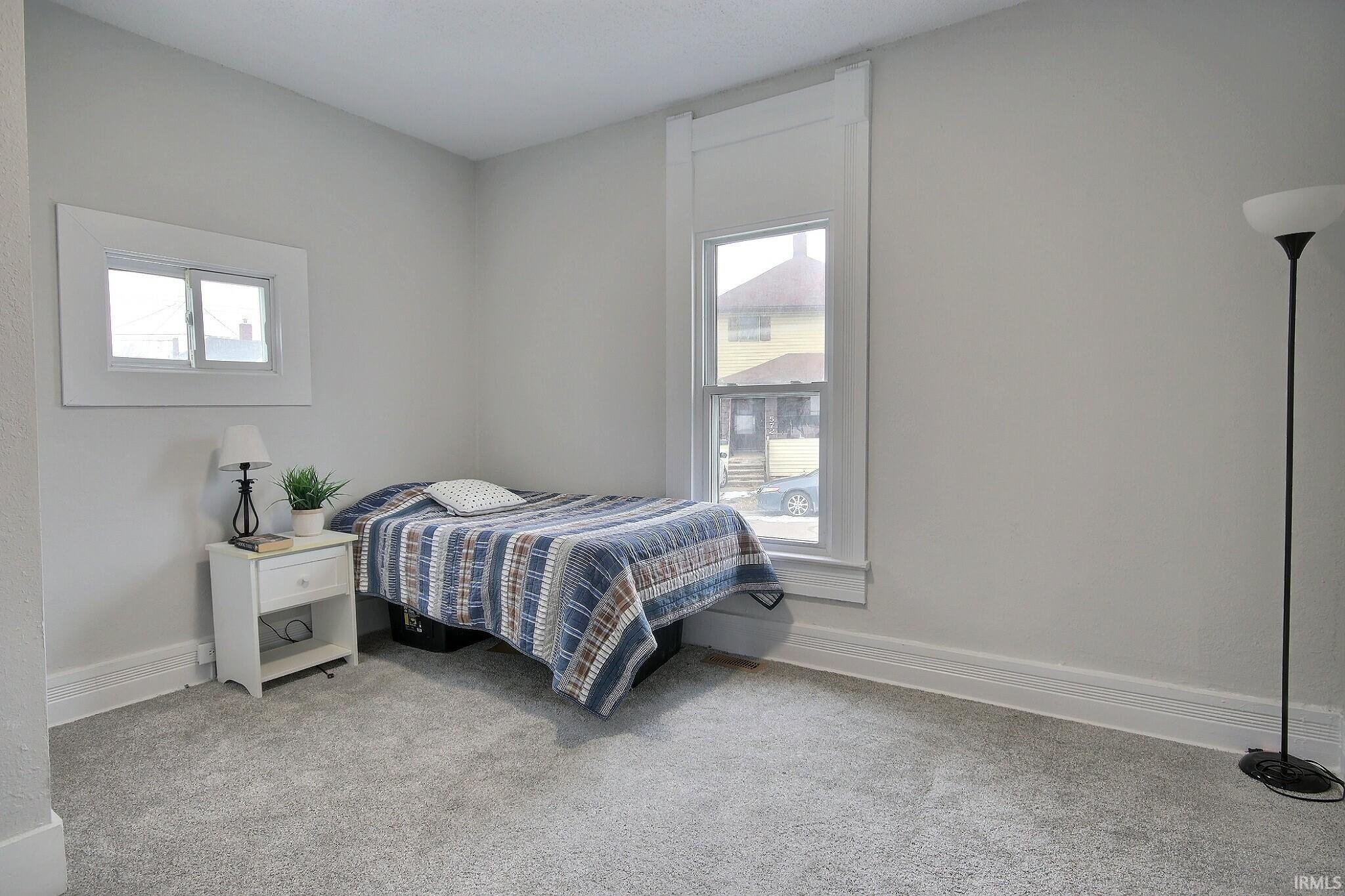 Bedroom with multiple windows and light colored carpet