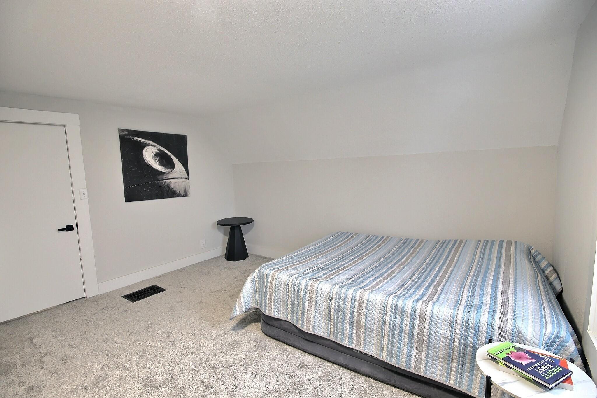 Carpeted bedroom featuring lofted ceiling and a textured ceiling