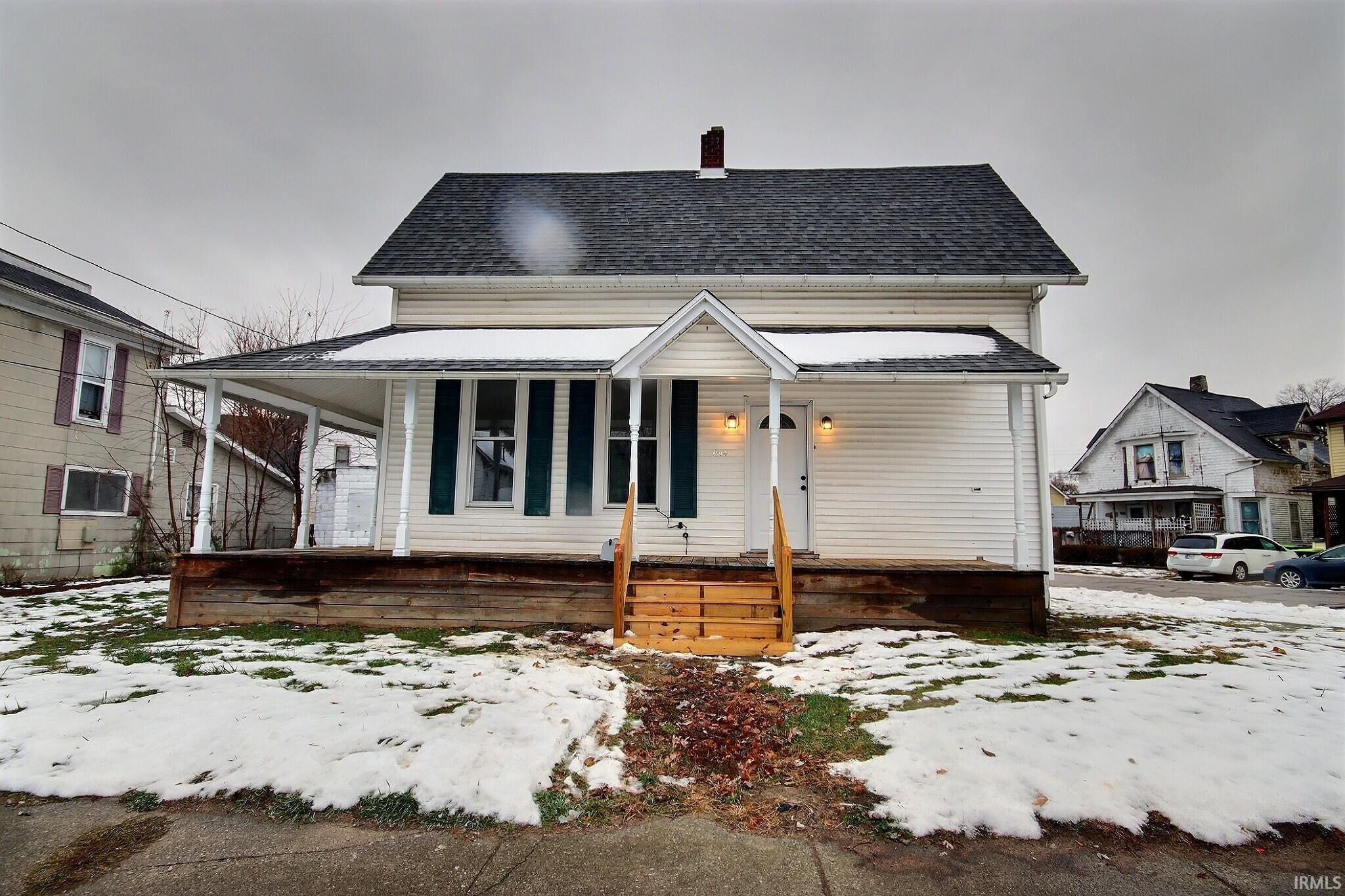 View of front of home with a porch, a chimney, and roof with shingles