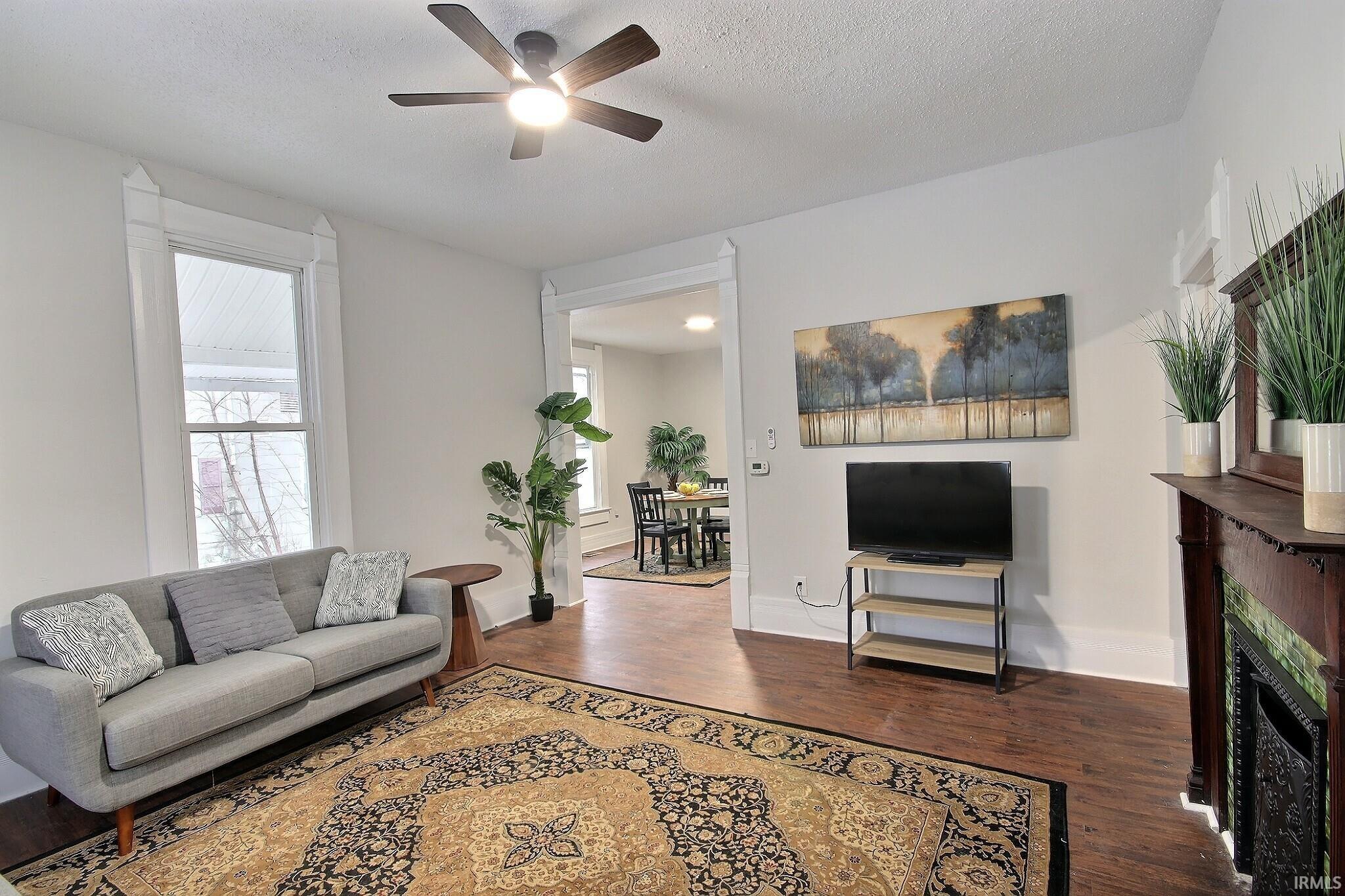 Living area featuring dark wood-style floors, a textured ceiling, and a ceiling fan