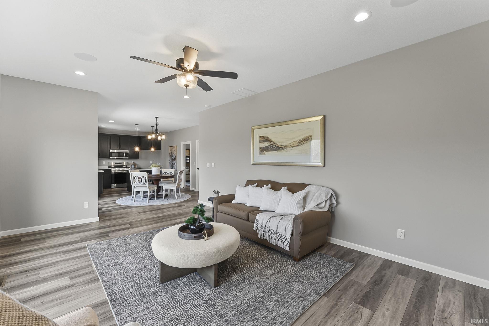 Living room with ceiling fan, dark wood-type flooring, and a chandelier
