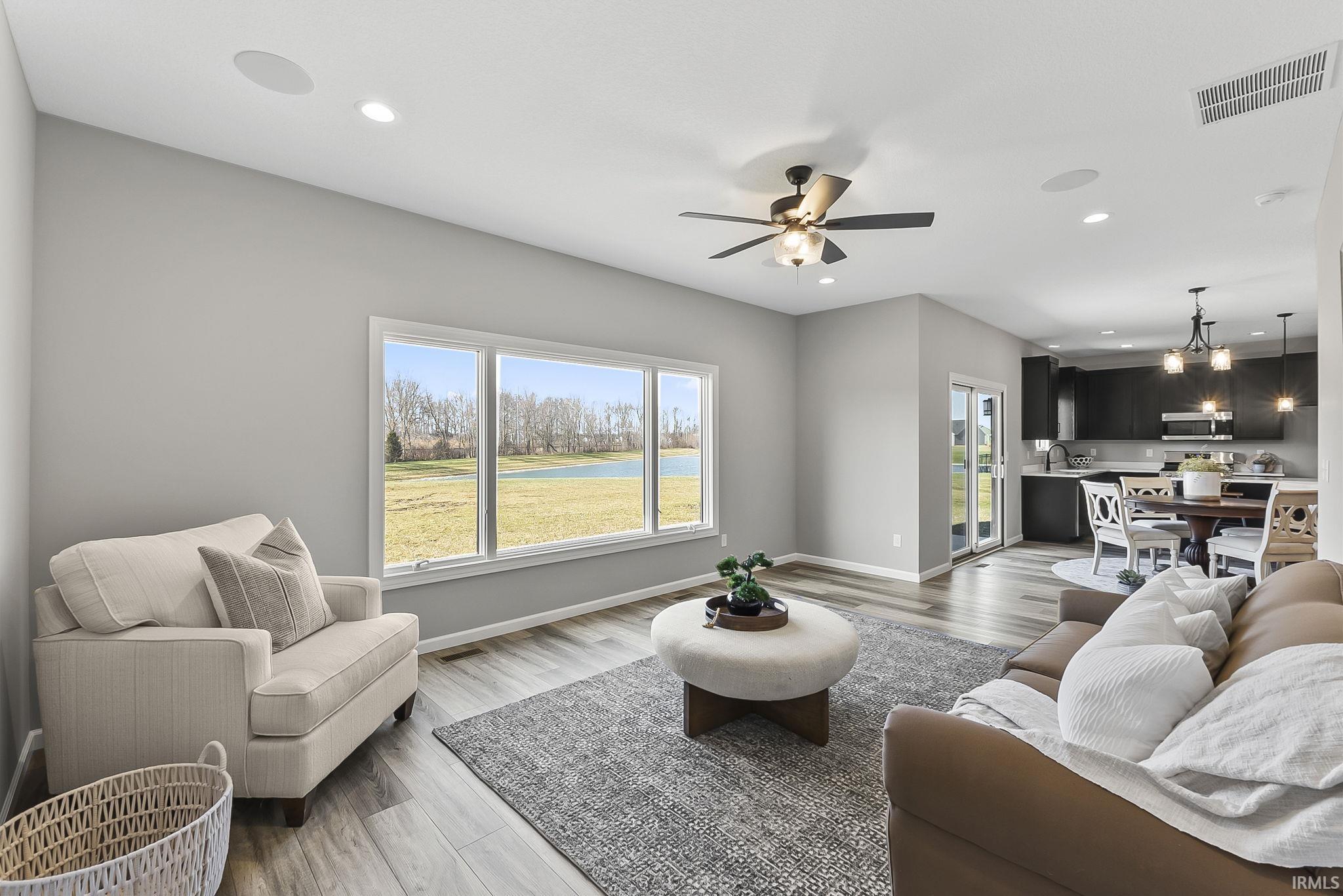 Living area with light wood-style flooring, ceiling fan, a water view, and healthy amount of natural light