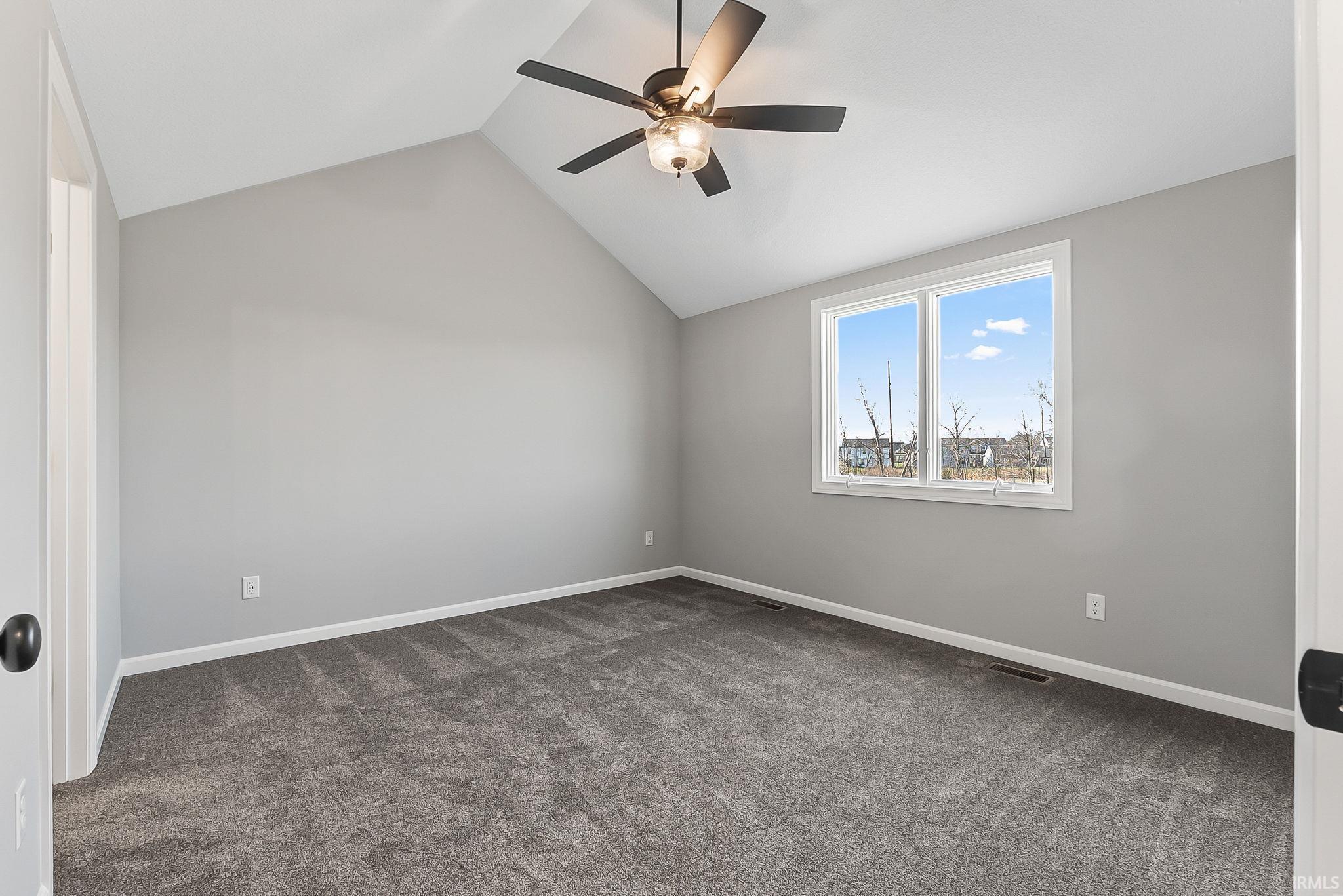 Unfurnished room featuring dark colored carpet and a ceiling fan