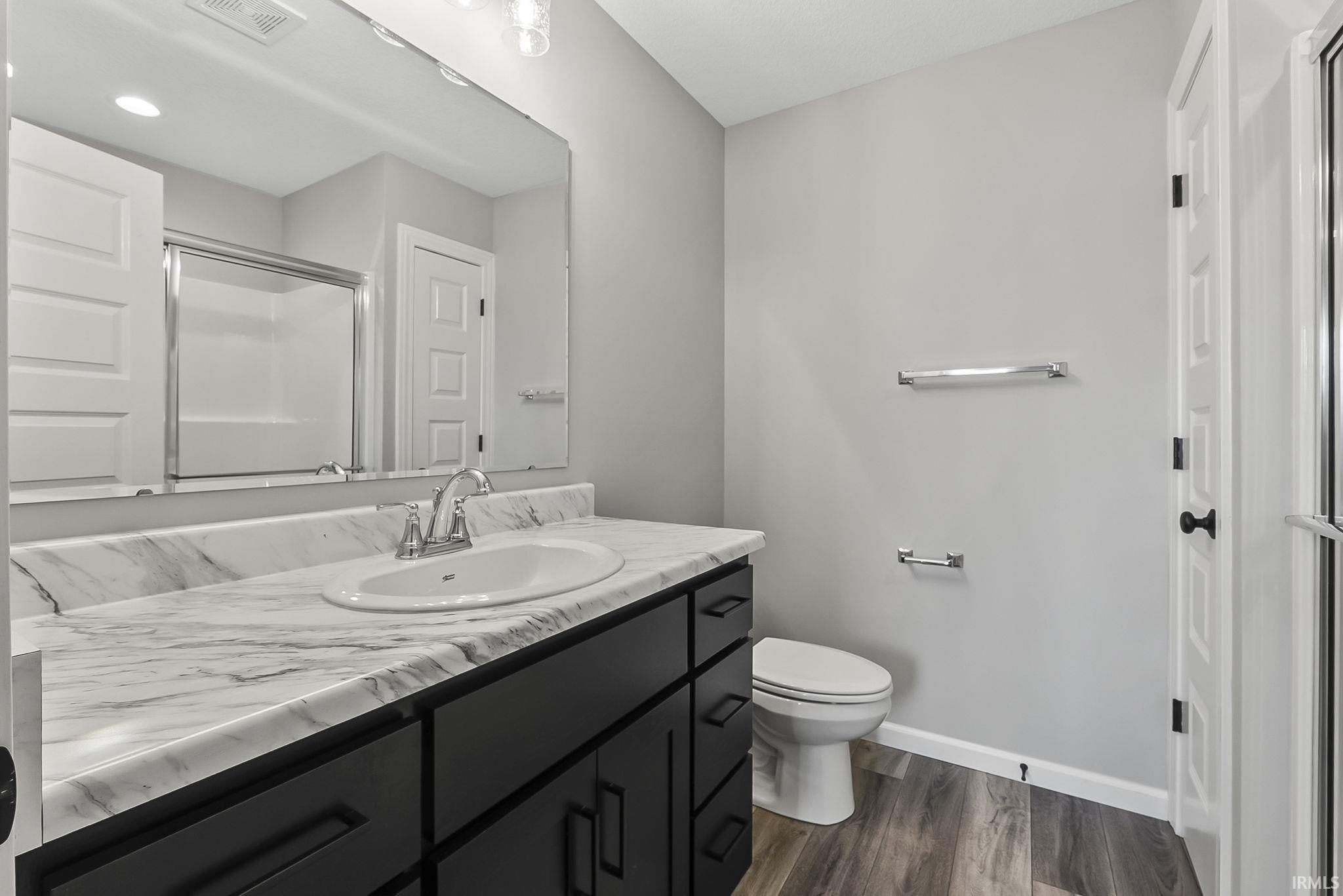 Full bath with vanity, dark wood finished floors, a shower stall, and a closet