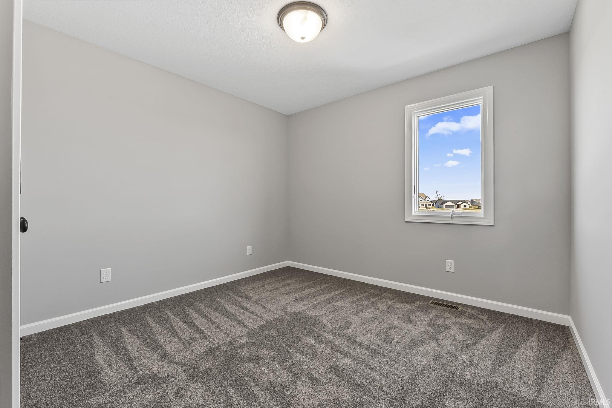 Empty room featuring baseboards and dark colored carpet