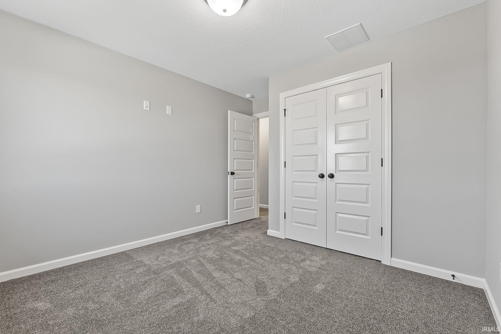 Unfurnished bedroom featuring a closet and dark colored carpet