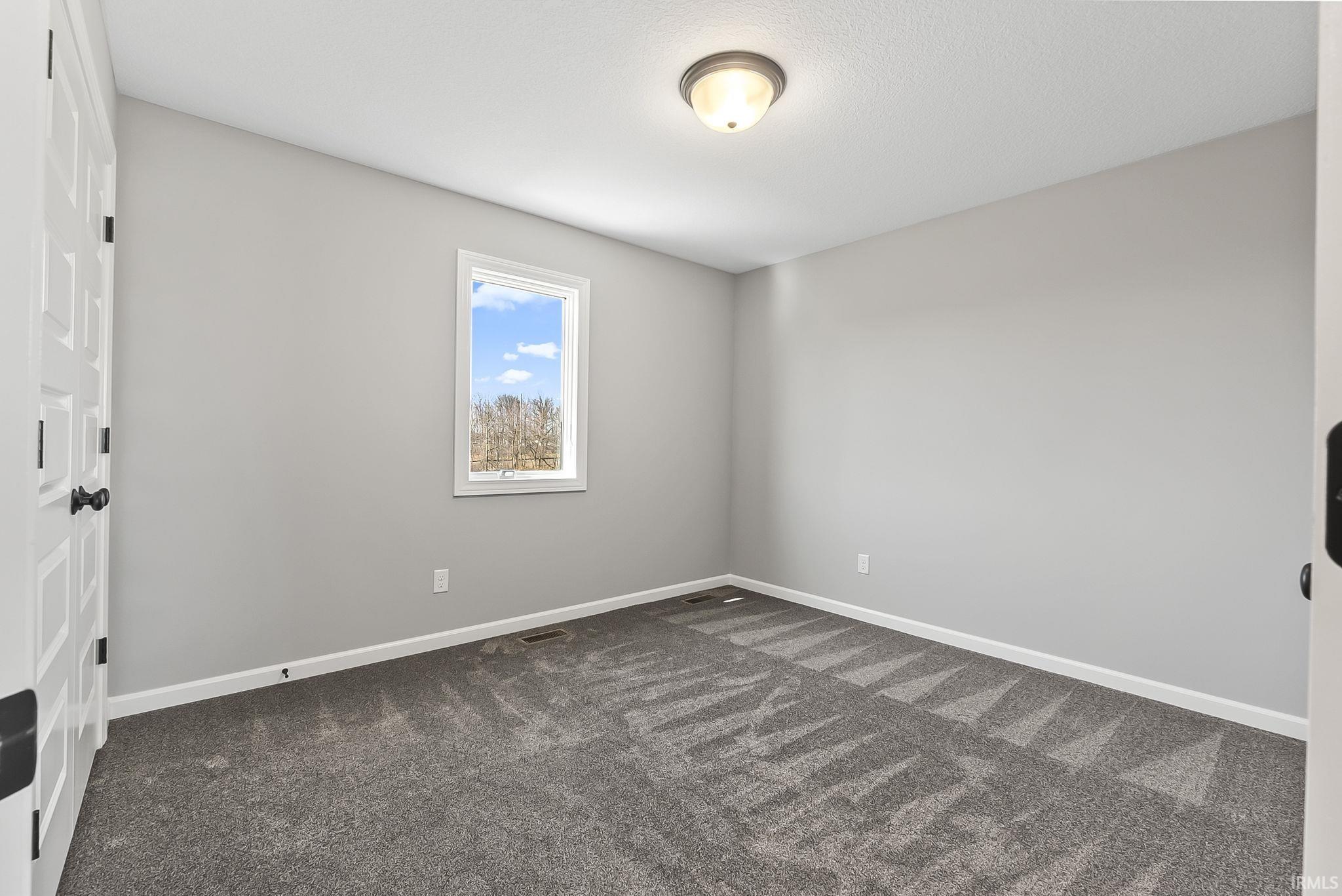 Spare room featuring baseboards and dark colored carpet