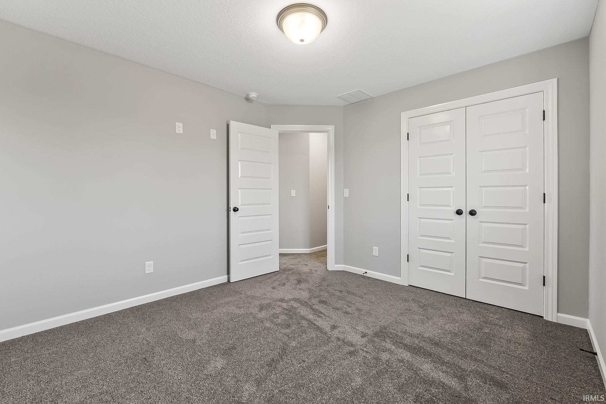 Unfurnished bedroom with dark carpet and a closet