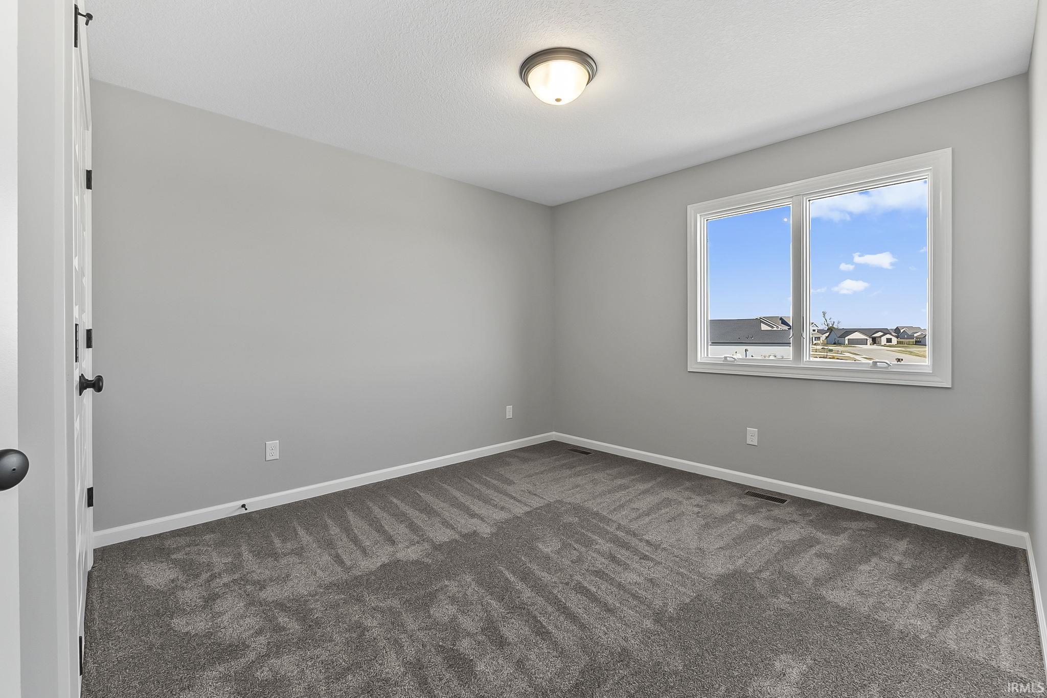 Unfurnished room with dark carpet and baseboards