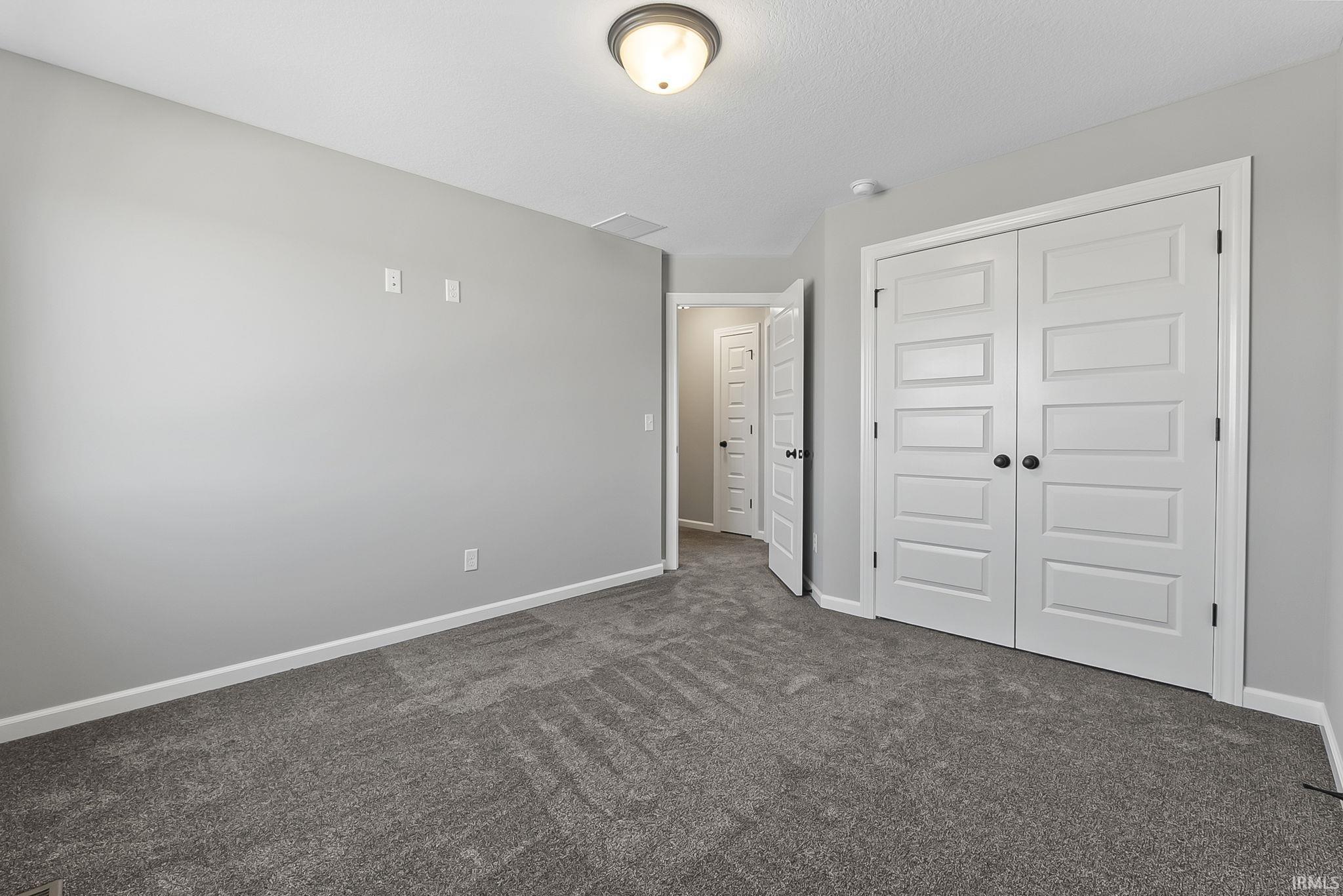 Unfurnished bedroom with dark carpet and a closet
