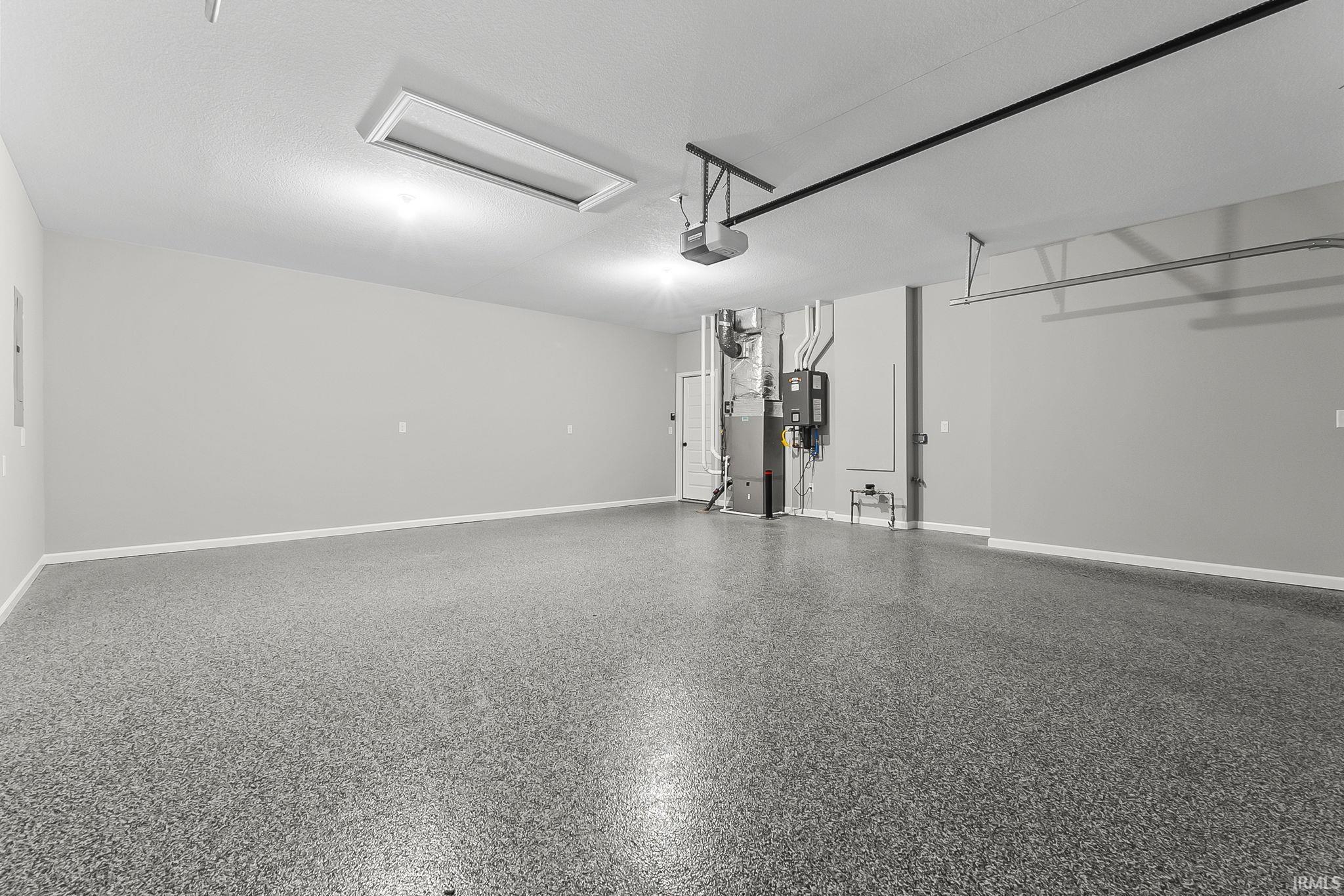 Garage featuring heating unit, water heater, and a garage door opener