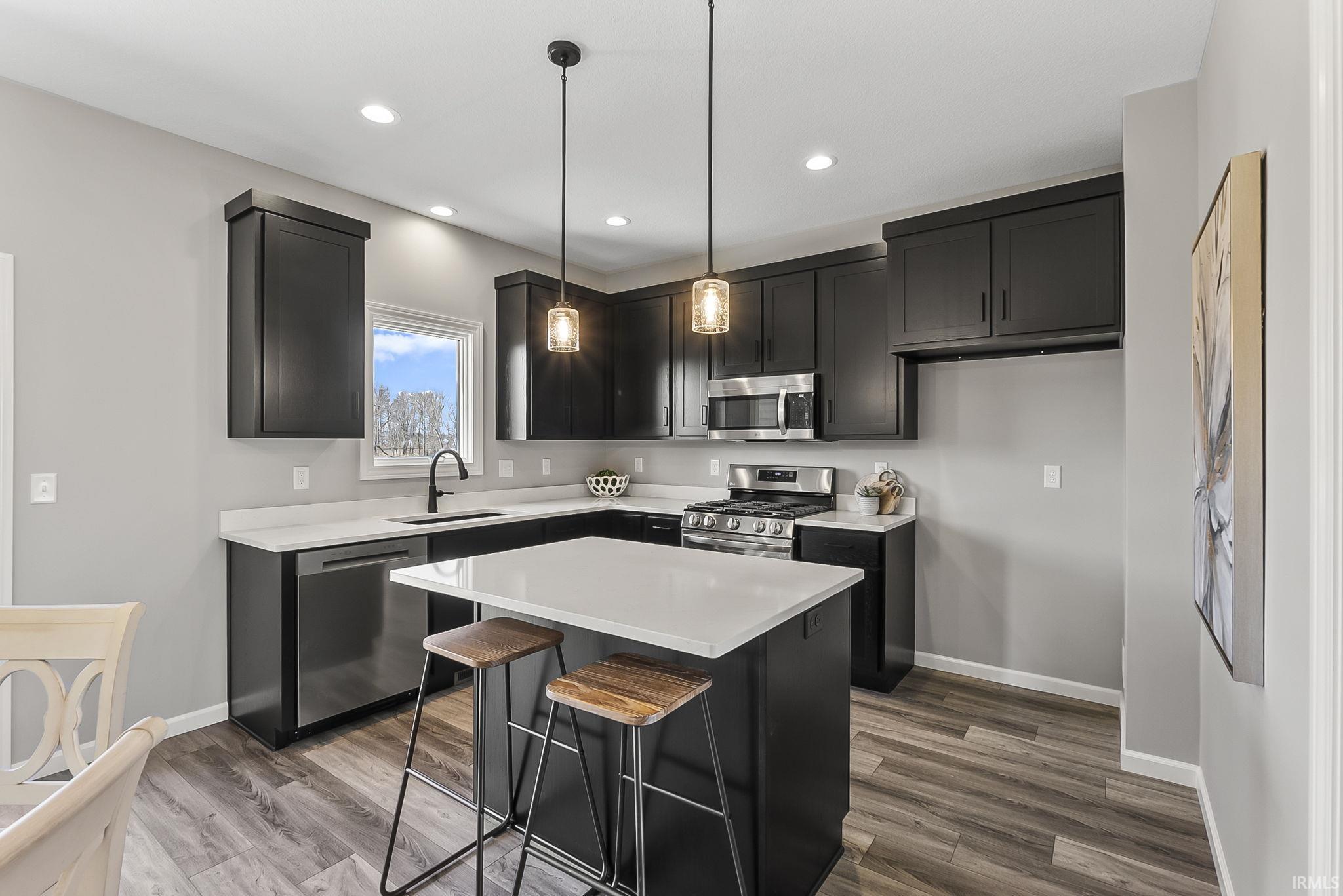 Kitchen featuring stainless steel appliances, a kitchen breakfast bar, light wood-type flooring, and a kitchen island