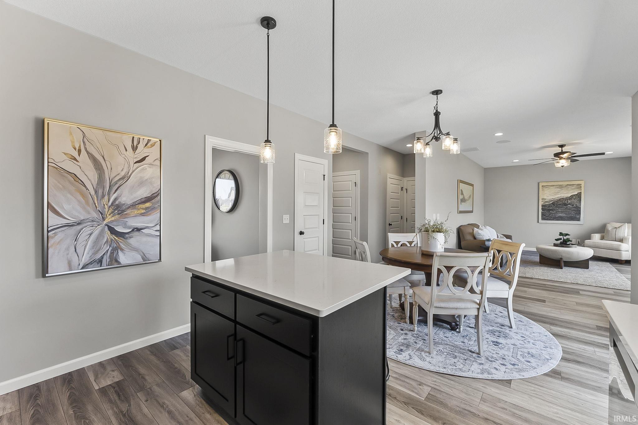 Kitchen featuring dark cabinets, open floor plan, light countertops, a kitchen island, and hanging lights